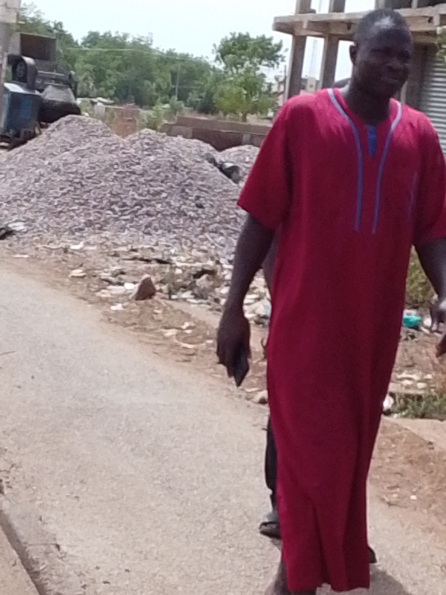 Man walks cracked road carrying object in Tamale Ghana