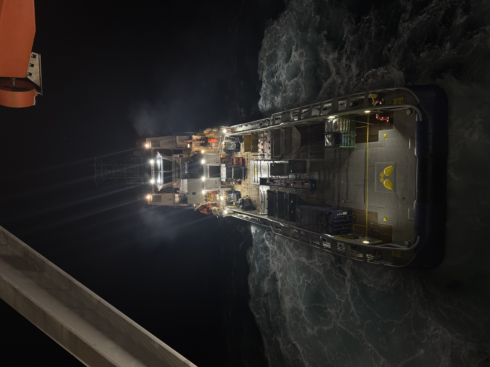 Night drone shot of a loaded supply vessel off Italy