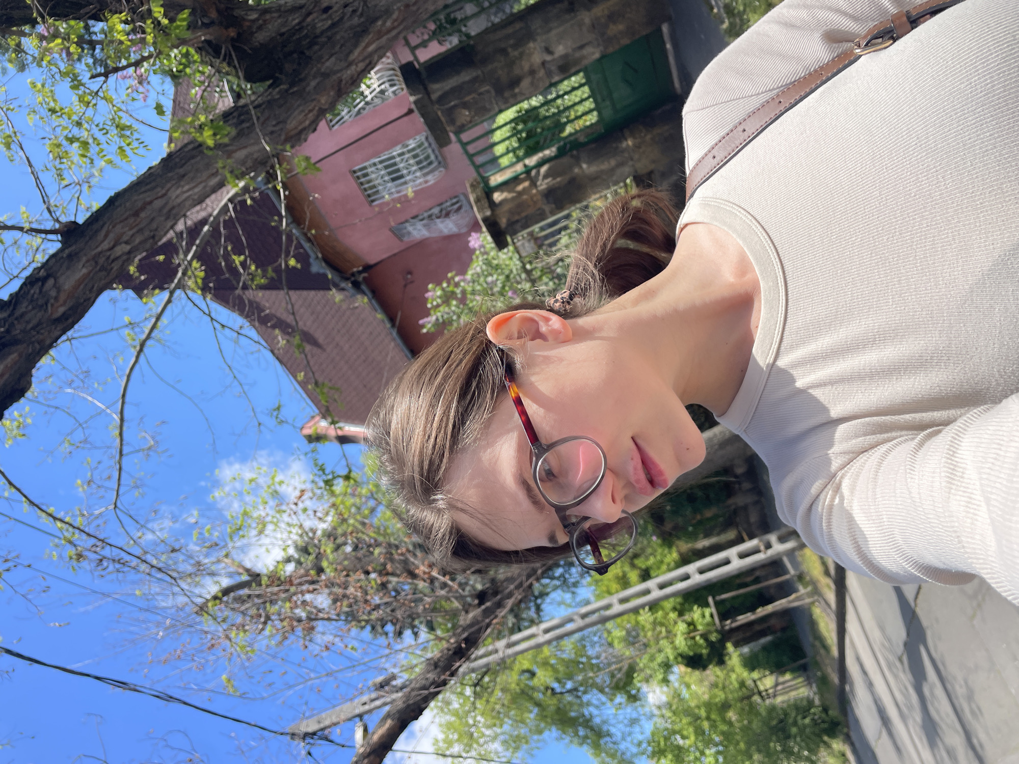 Woman documents sunny morning walk through residential Budapest neighborhood