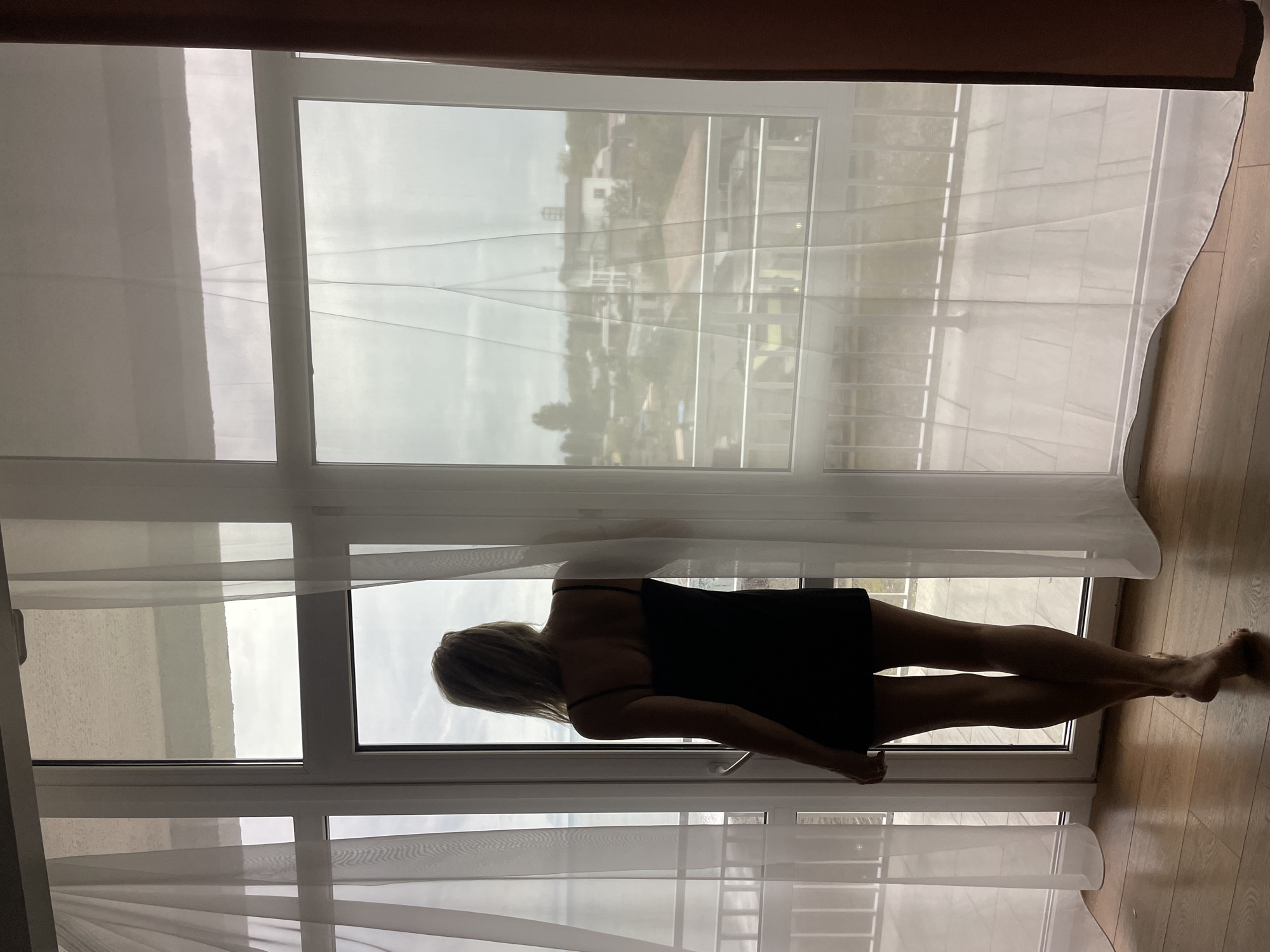 Woman opens curtains at dawn in Giachrypsh apartment