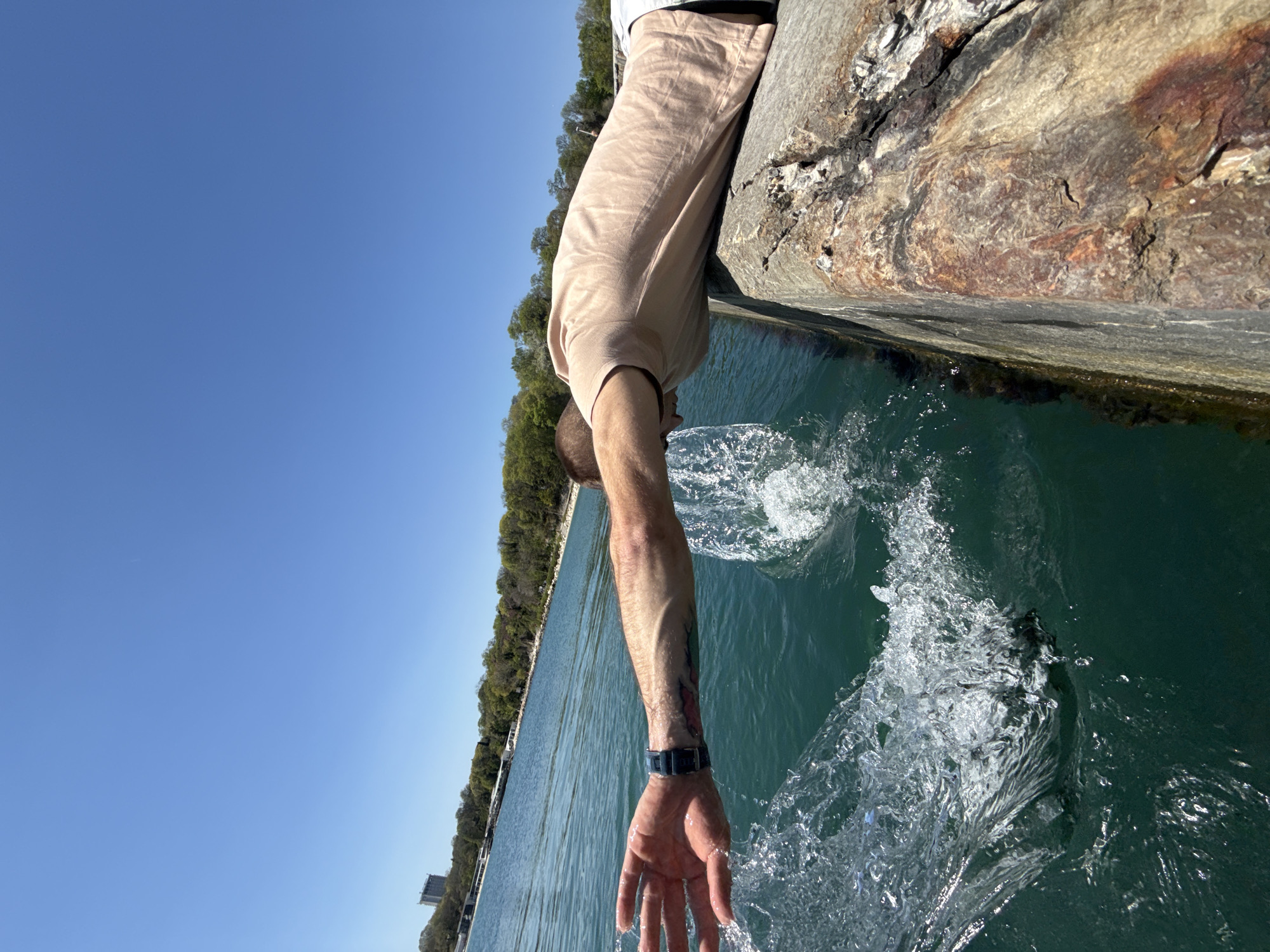 Man touches Black Sea water from pier in Varna