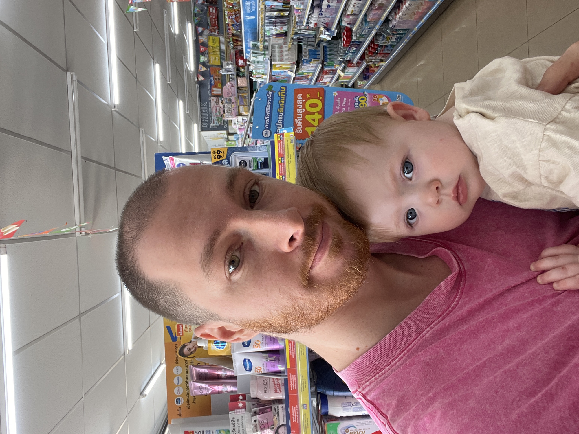 Man holds child in Thailand convenience store early morning