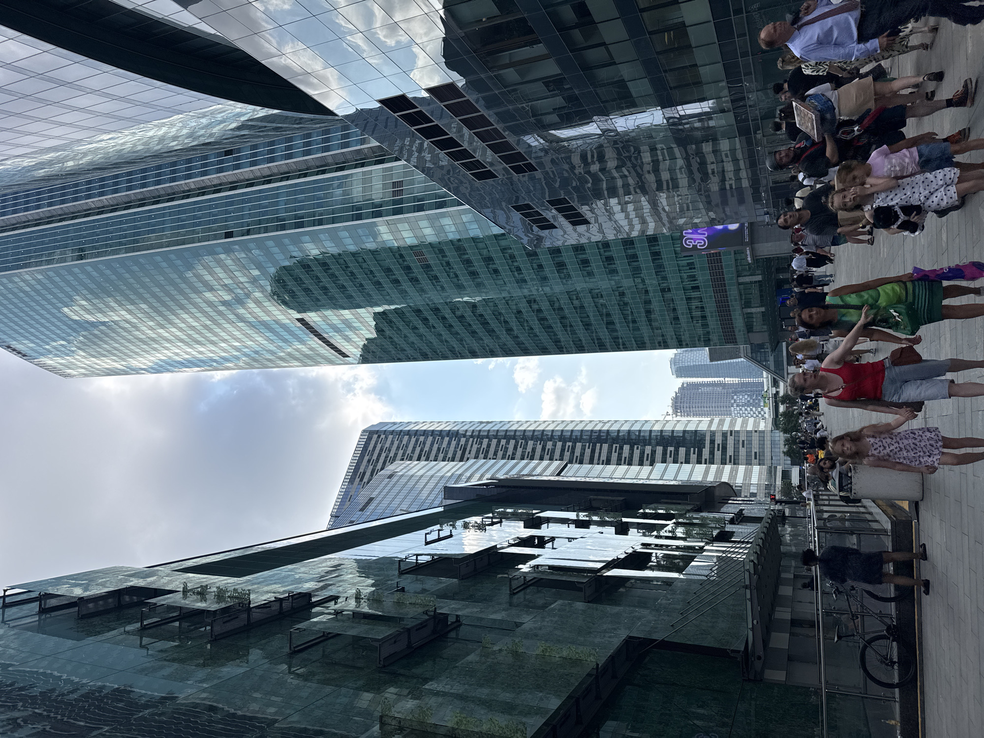 Busy pedestrian walkway cuts through a gleaming downtown high-rise district
