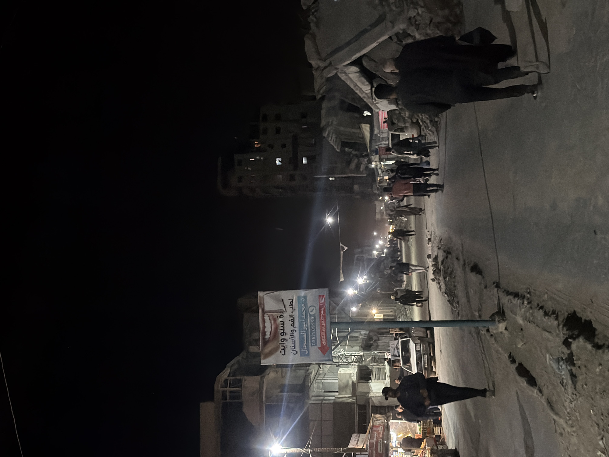 Pedestrians navigate damaged Gaza City streets at night