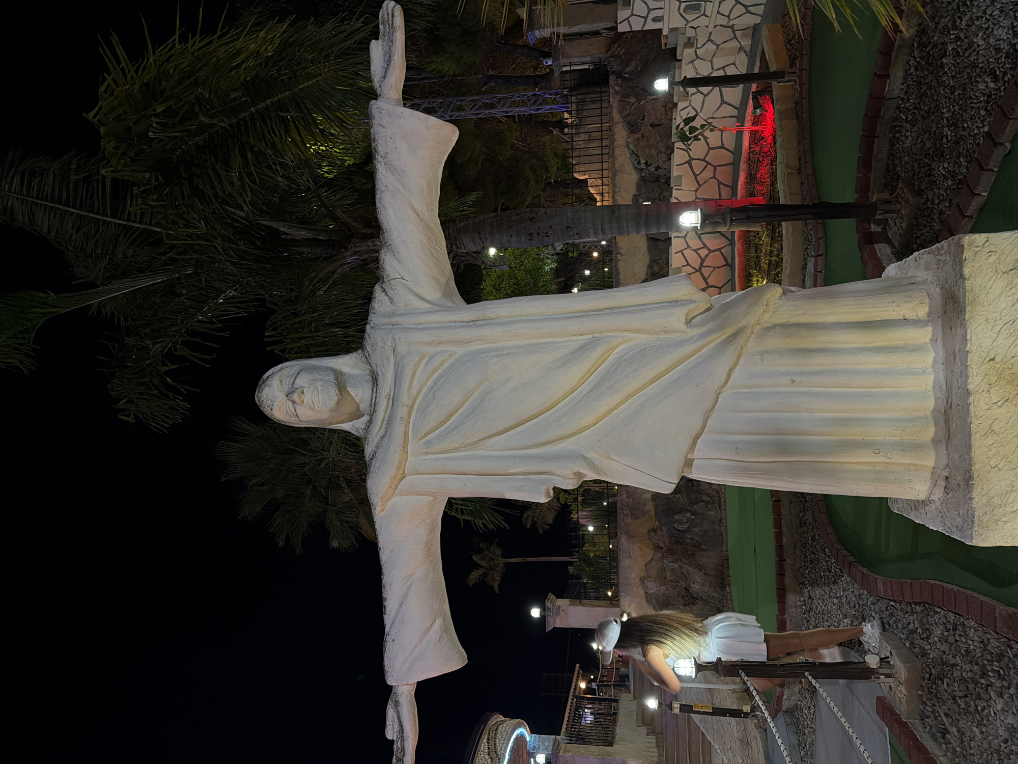 Nighttime mini-golf with a towering Jesus statue as centerpiece