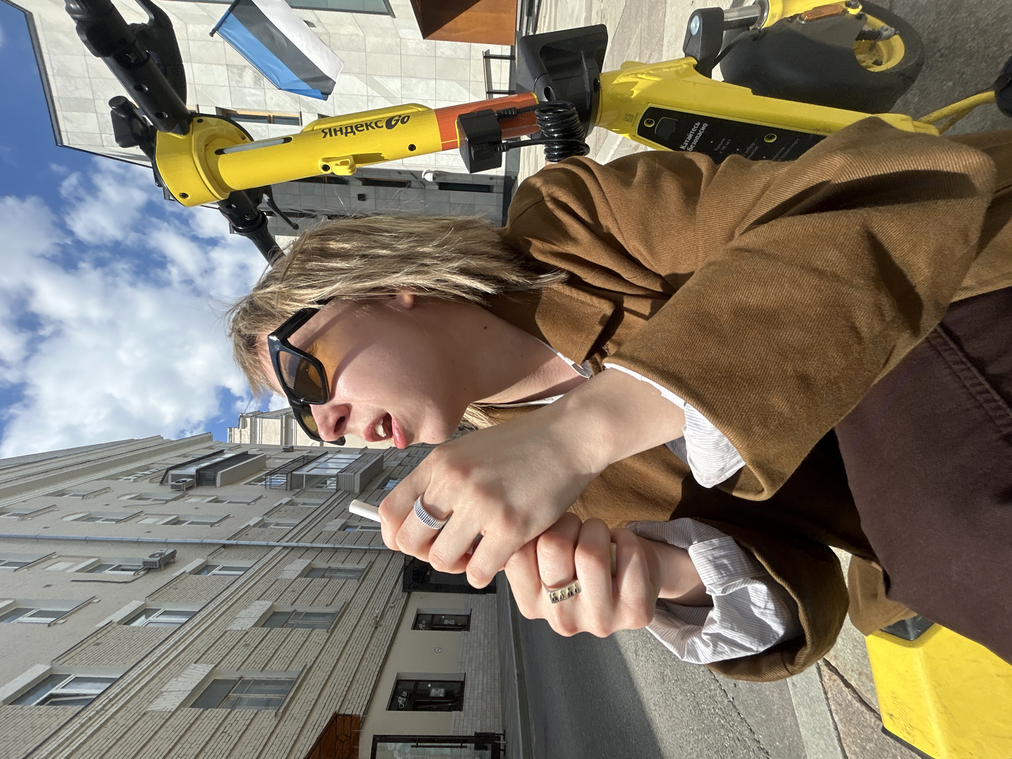 Woman on Yandex scooter smoking in urban setting