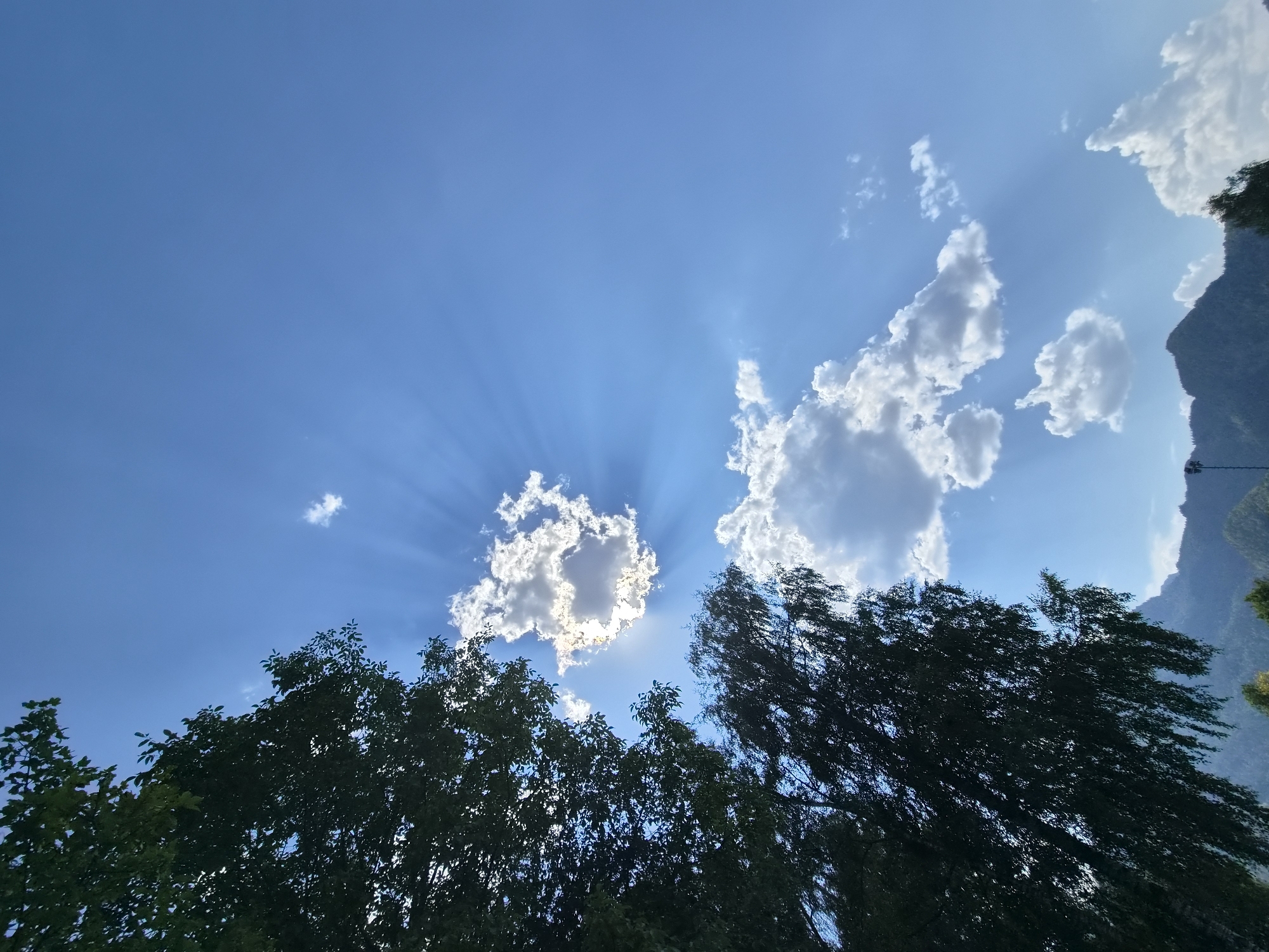 Sun, clouds, and rays over Landl on a bright August afternoon