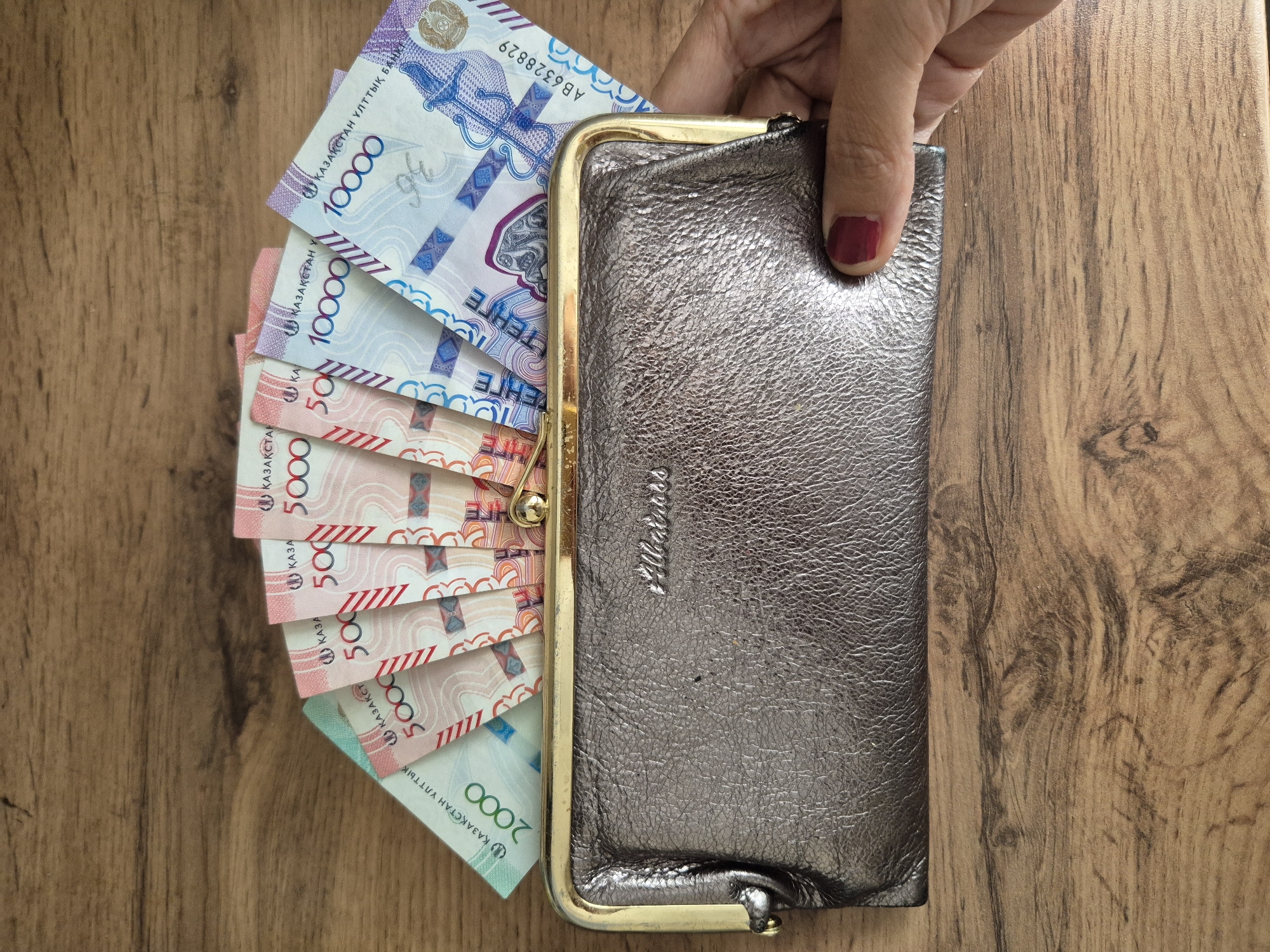 Person counts stack of Kazakhstani tenge banknotes in Kokshetau