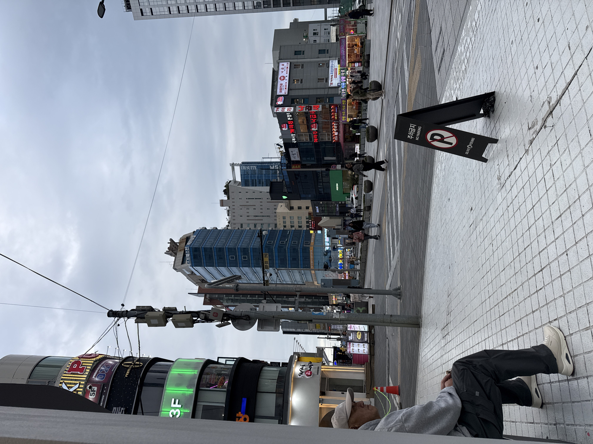 Person lying on sidewalk in Busan commercial district