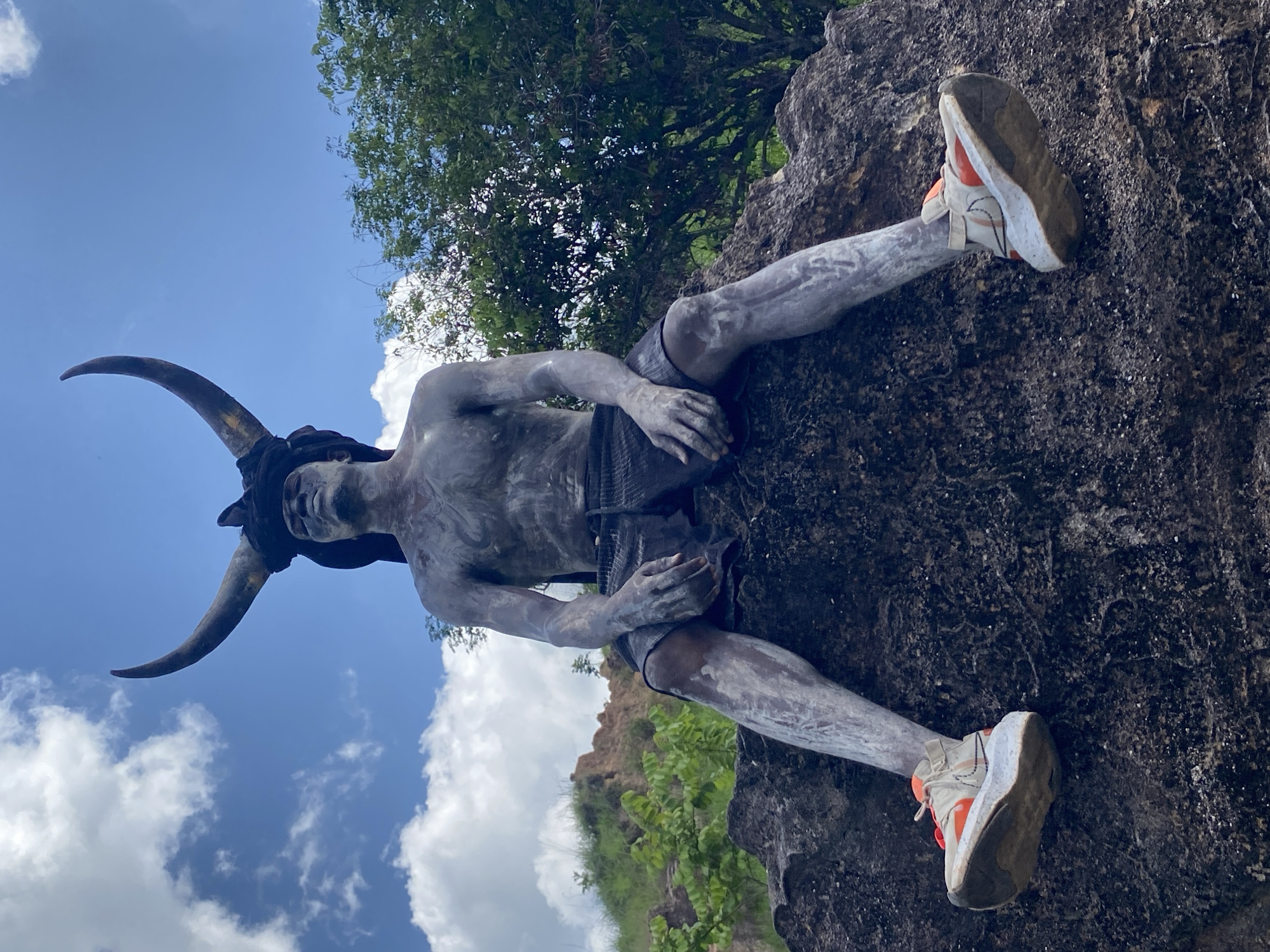 Person in grey paint, horns spotted on rocks in Nigeria