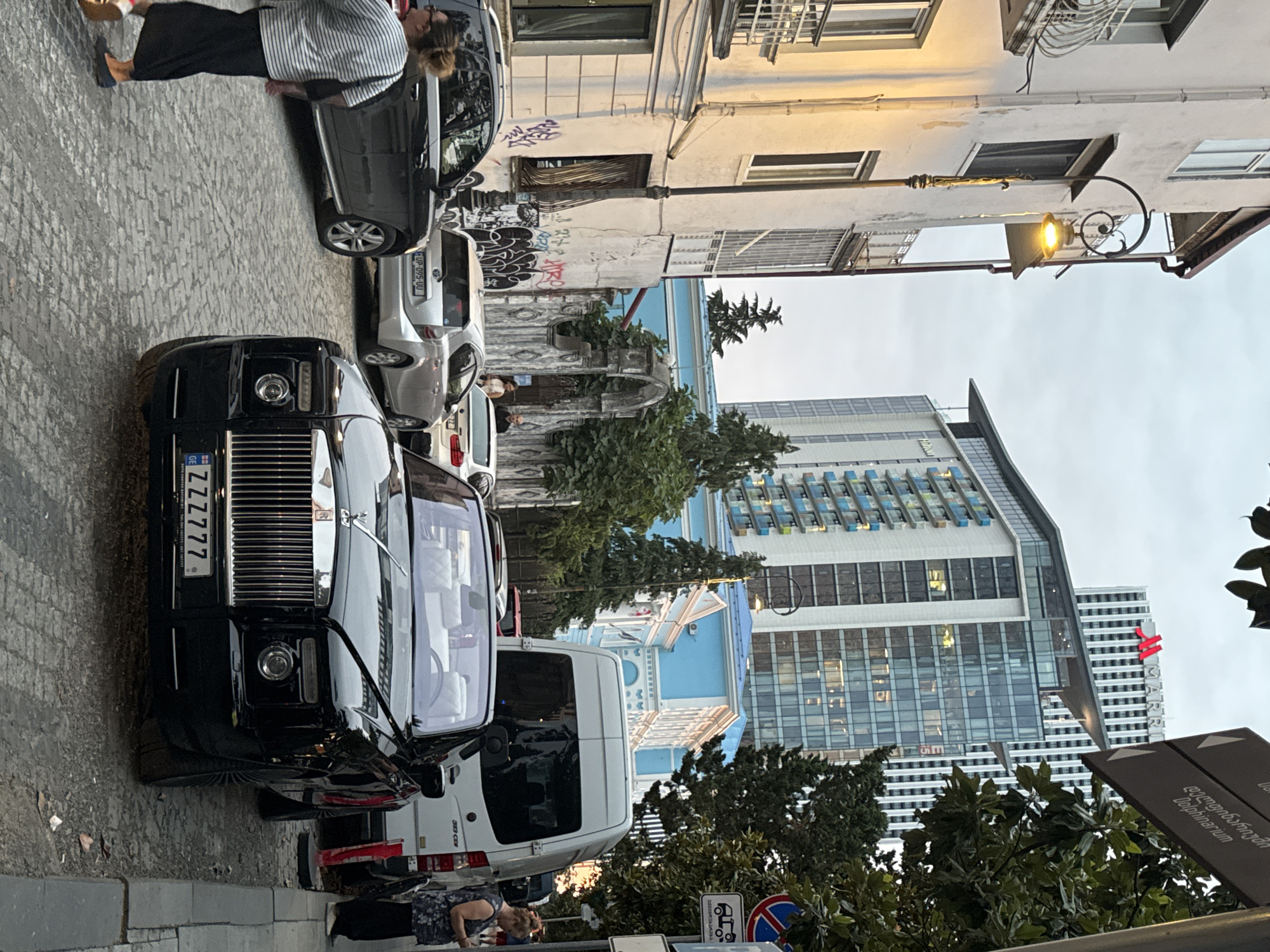 Cat on a Vespa, Rolls-Royce nearby — Batumi street scene