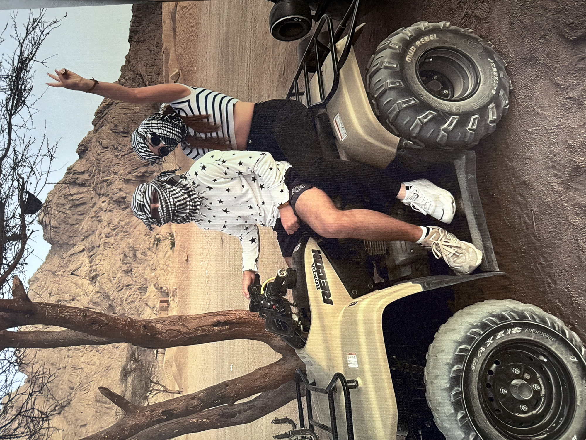 Two people on a Honda ATV in a rocky desert landscape