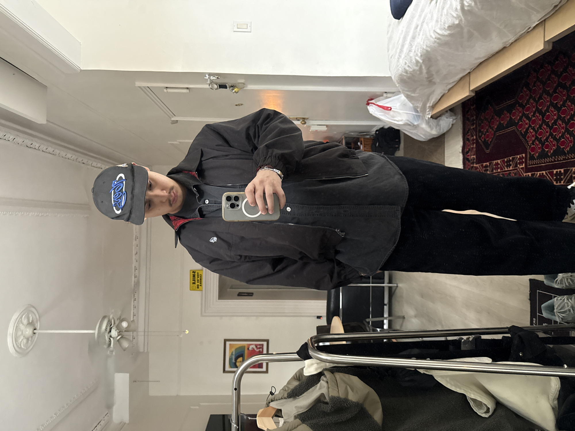 Person takes selfie wearing logo baseball cap in NYC apartment
