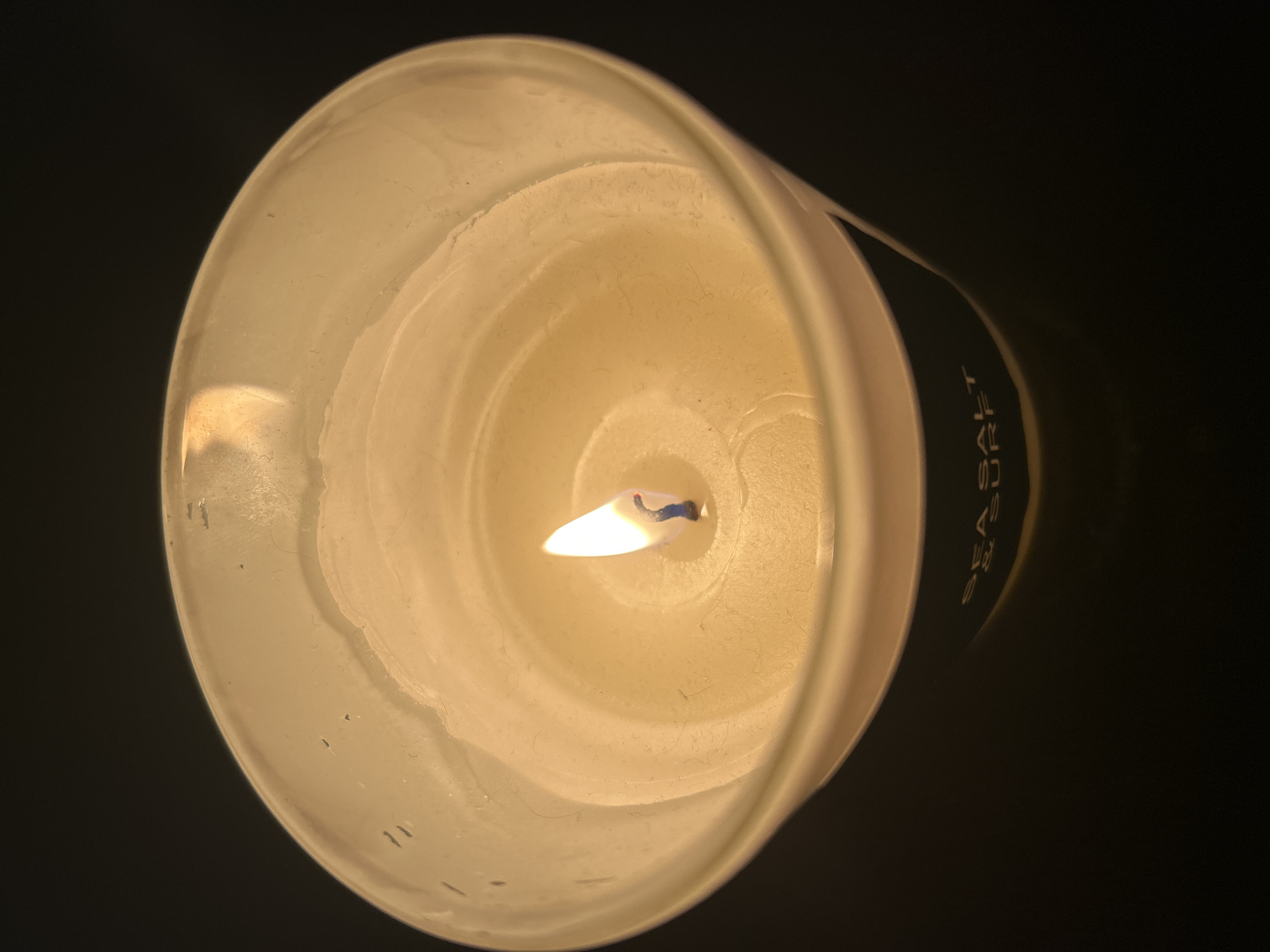 Close-up top-down shot of a candle burning in a glass jar.