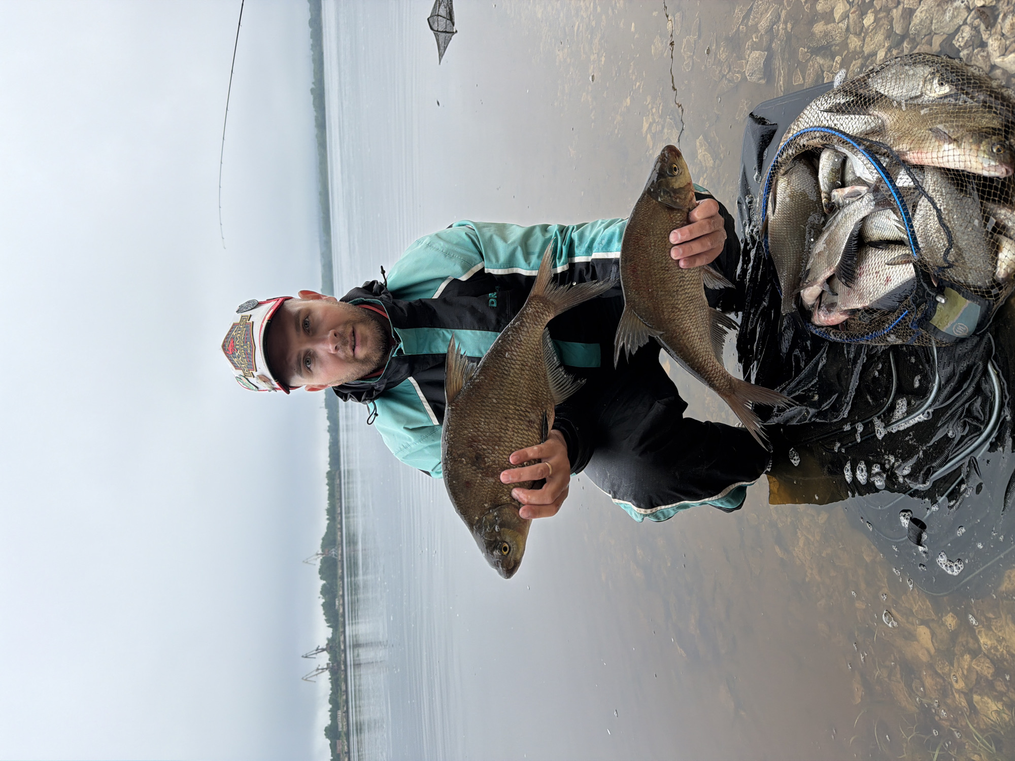 Fisherman displays catch in shallow waters near Chaikovsky, Russia