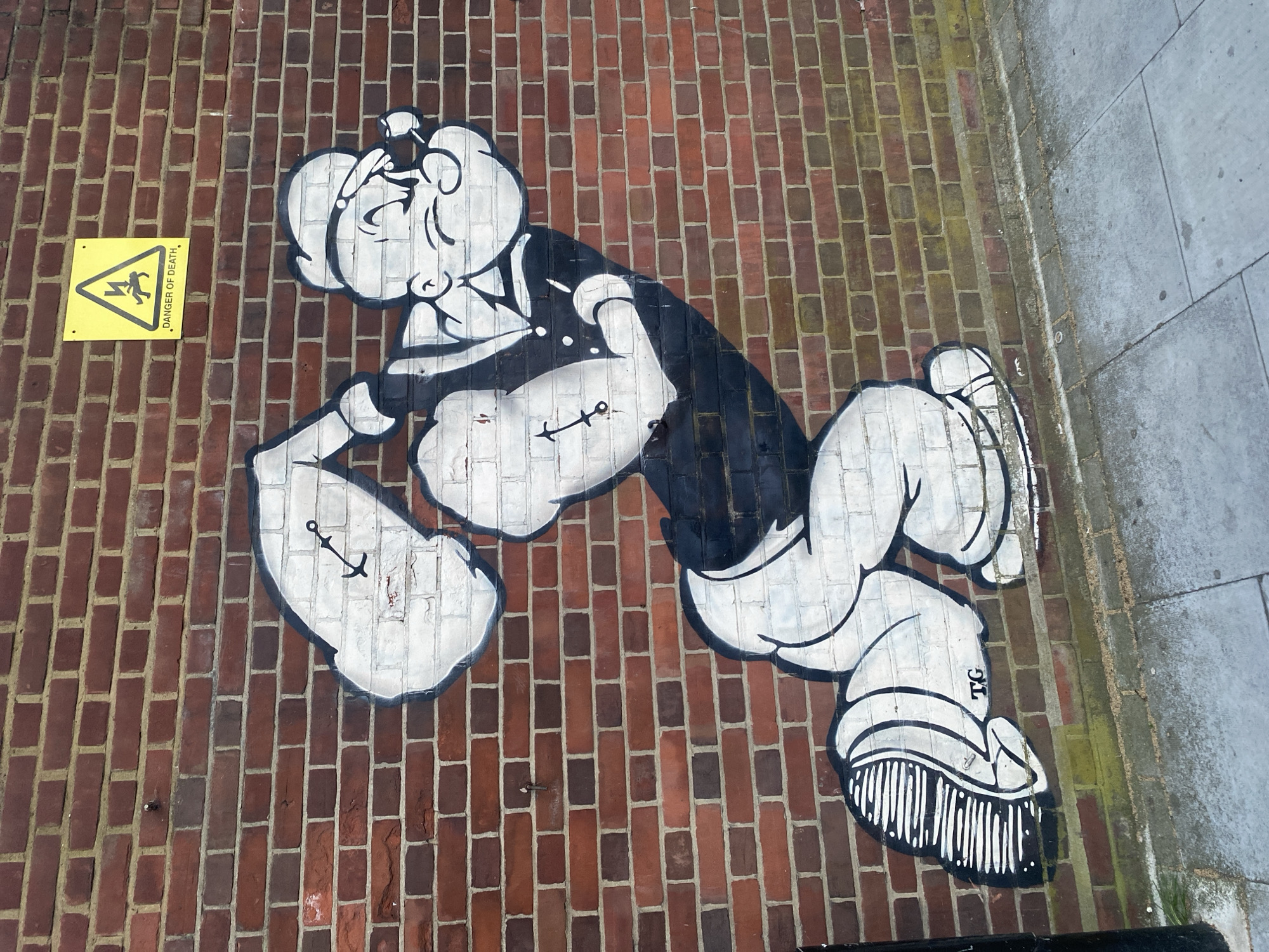 Popeye graffiti spotted on London brick wall near warning sign