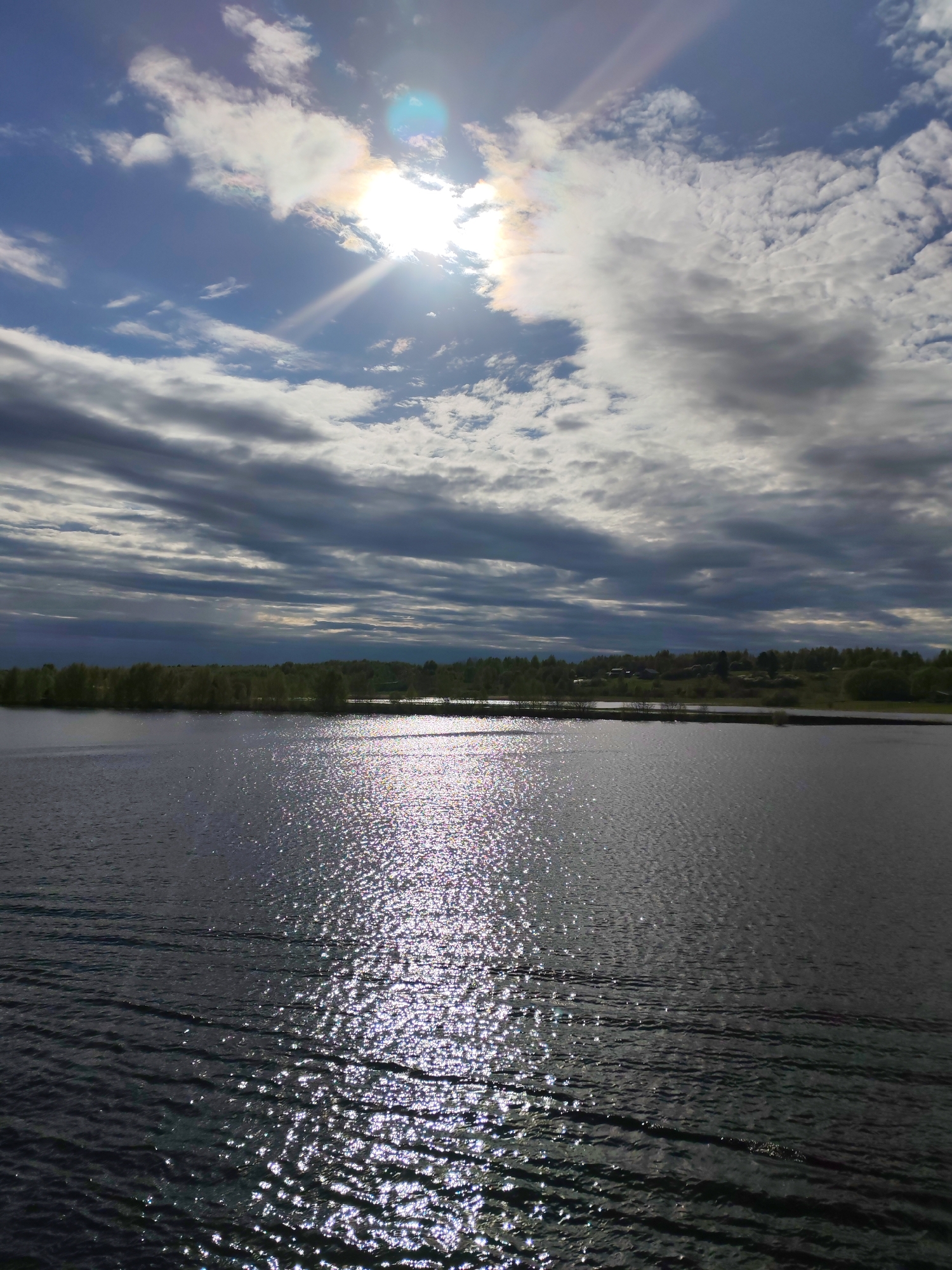 Sun rays pierce clouds over water in Zelonaya Roshcha
