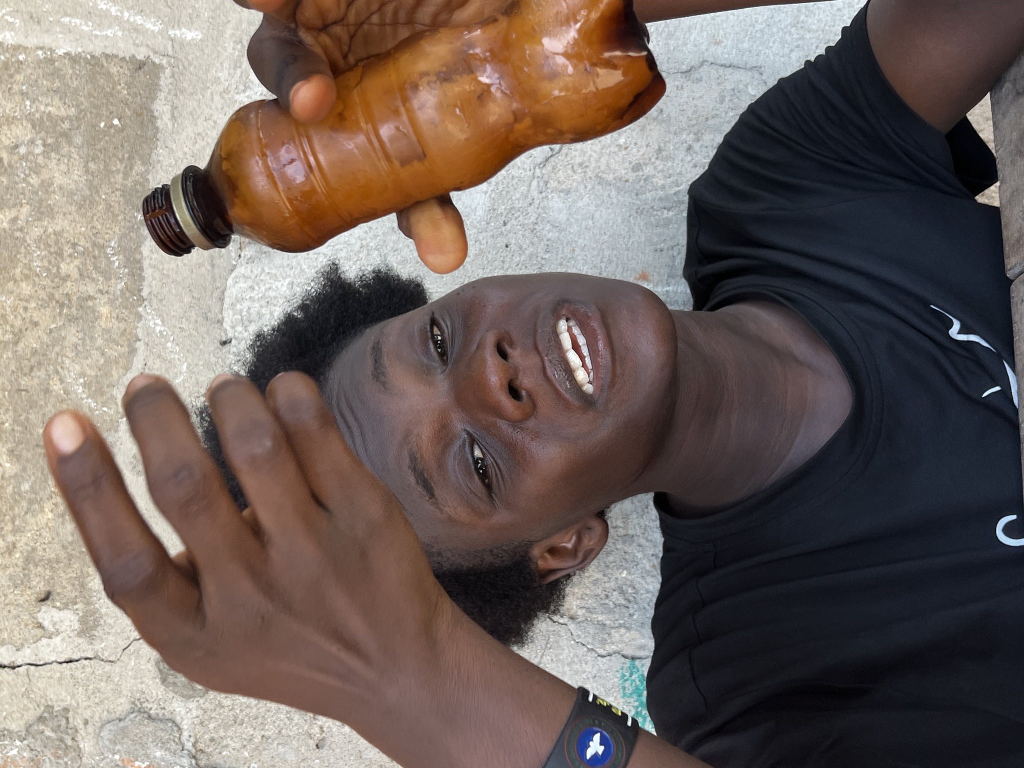 Person with bottle rests on concrete in Badagry