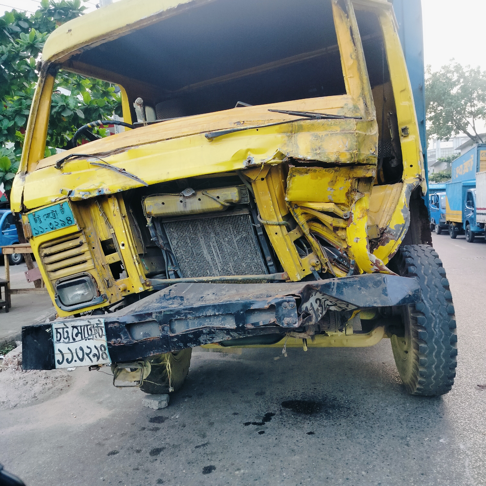 Severely damaged yellow truck documented with crushed front end