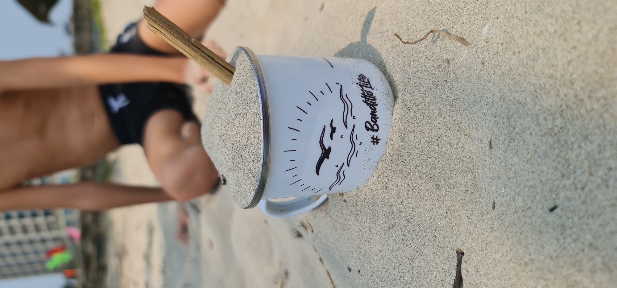 Child plays with sand-filled mug on Đà Nẵng beach