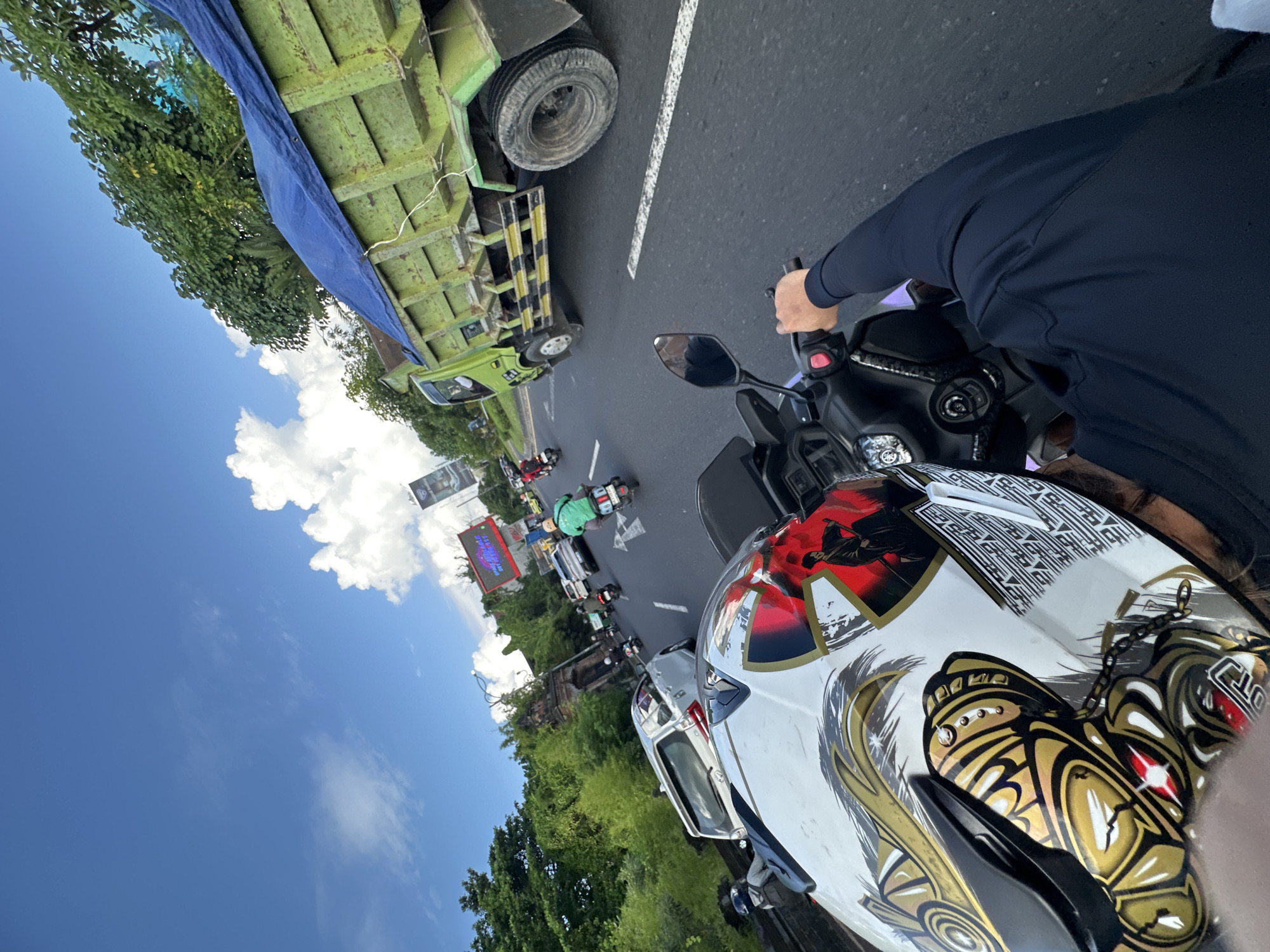 Motorcyclist with ornate helmet rides through Kuta, Indonesia