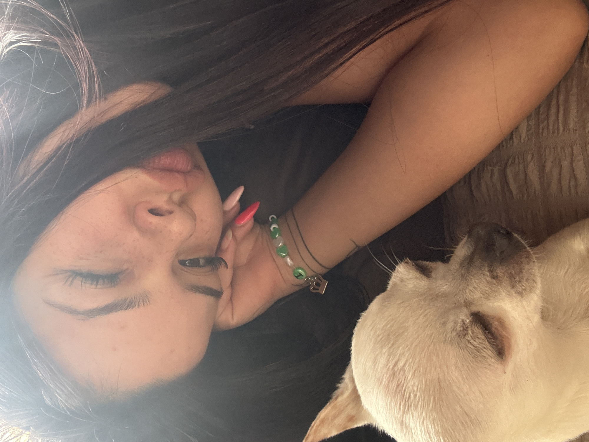 Woman takes selfies with white dog on sofa in Bulgaria
