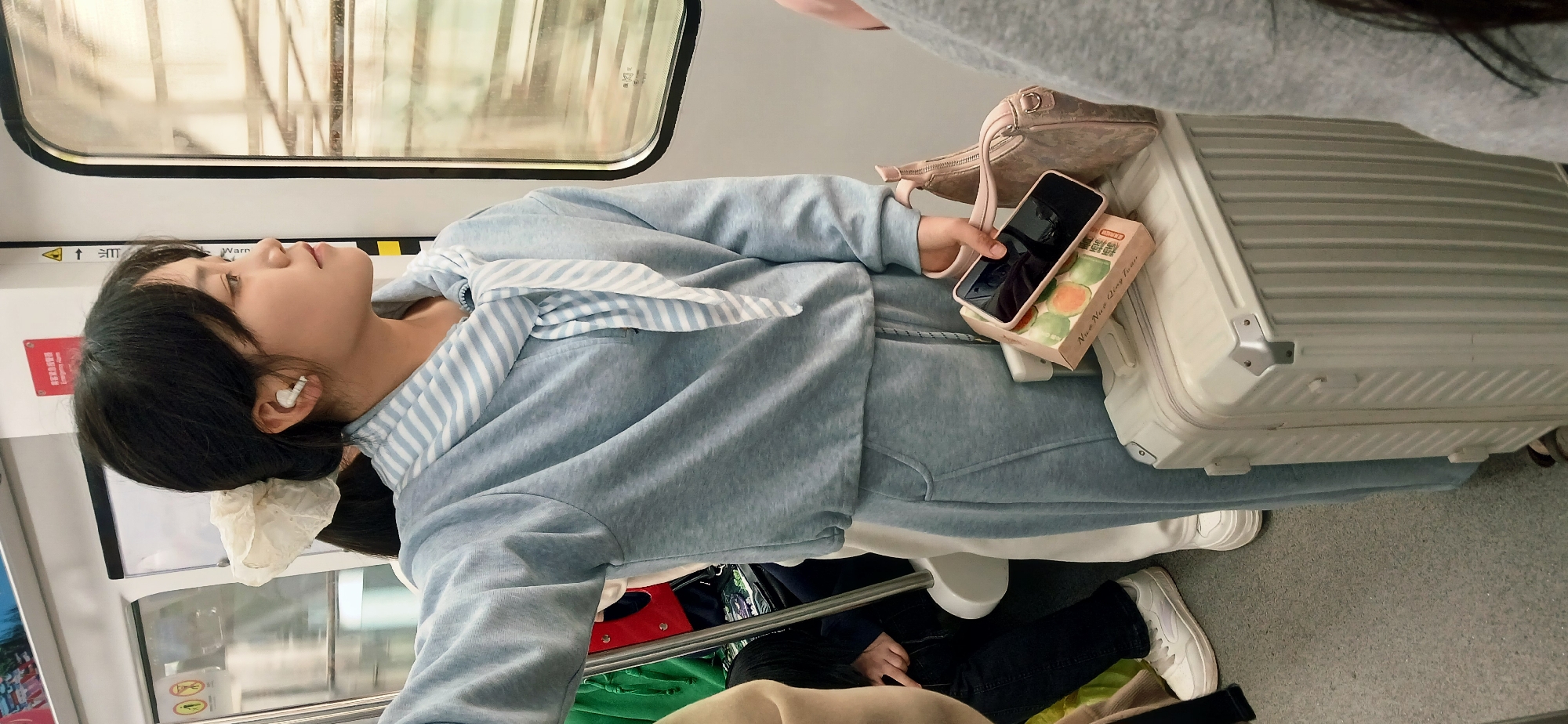 Woman rests on suitcase during subway journey in Chongqing