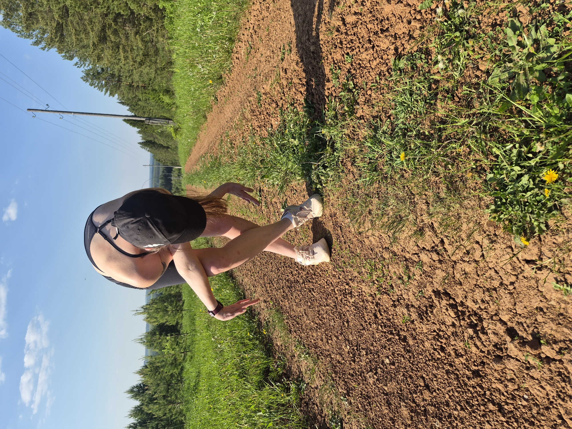 Woman exercising on rural dirt road amid green landscape