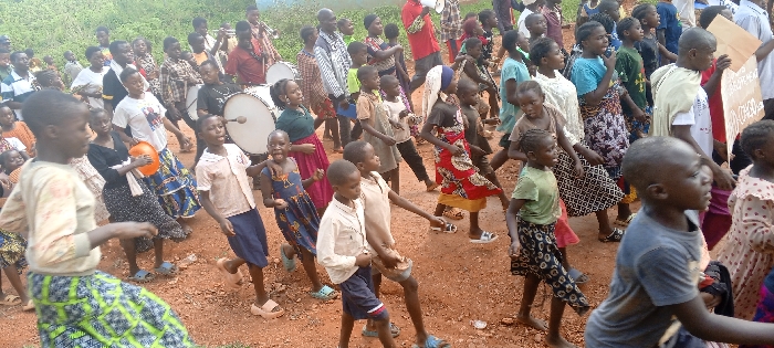Children and adults march with banners in DRC communities