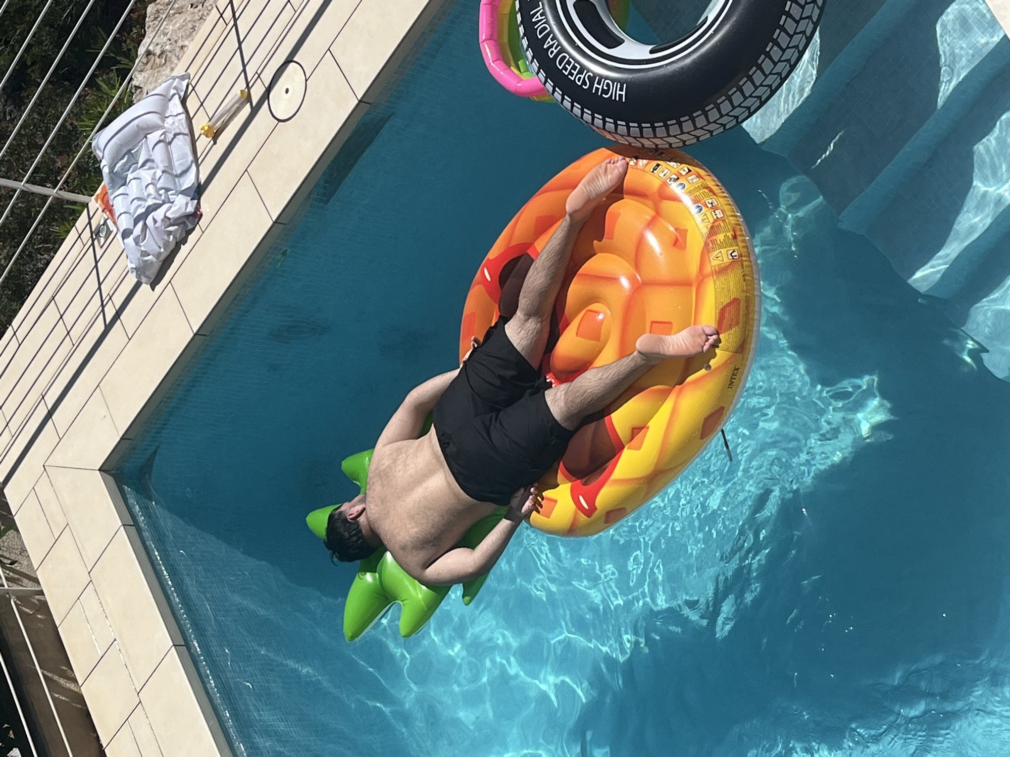 Man enjoys afternoon pool time on pineapple float in Spain