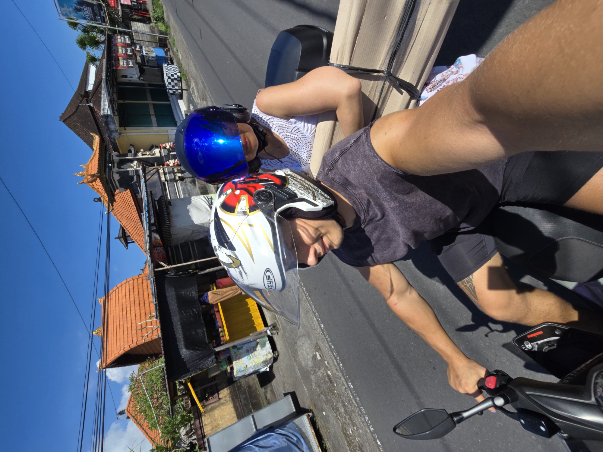 Two people take motorcycle selfies in sunny Kediri, Indonesia