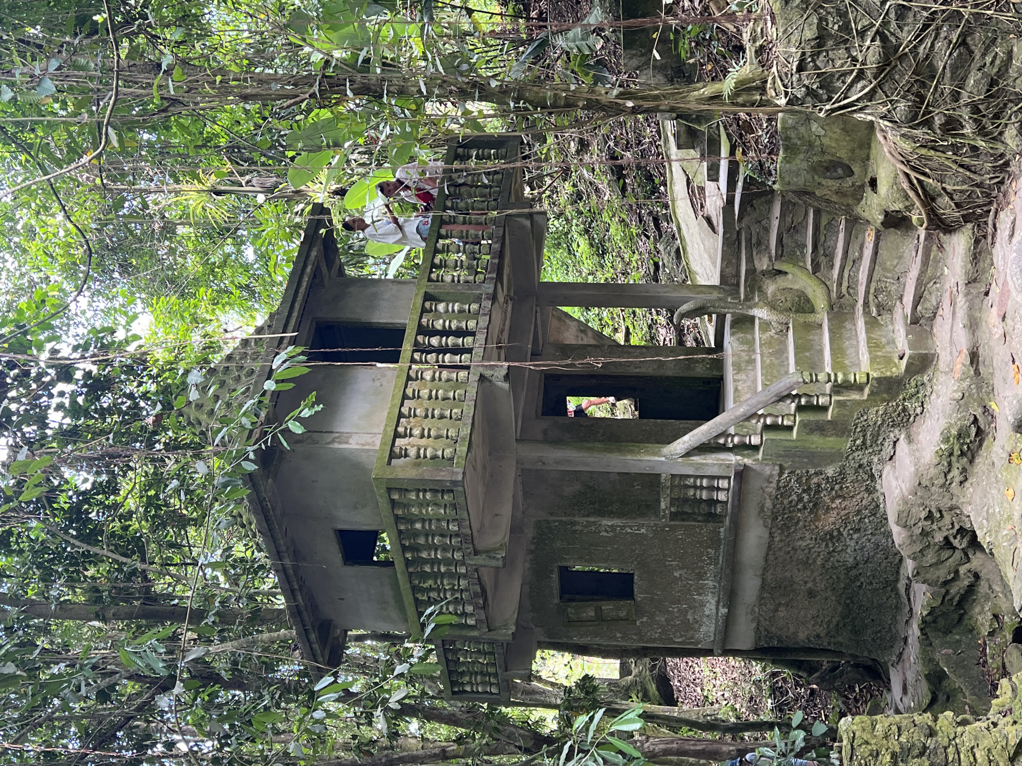 Overgrown jungle shrine with stone statues in Ko Samui