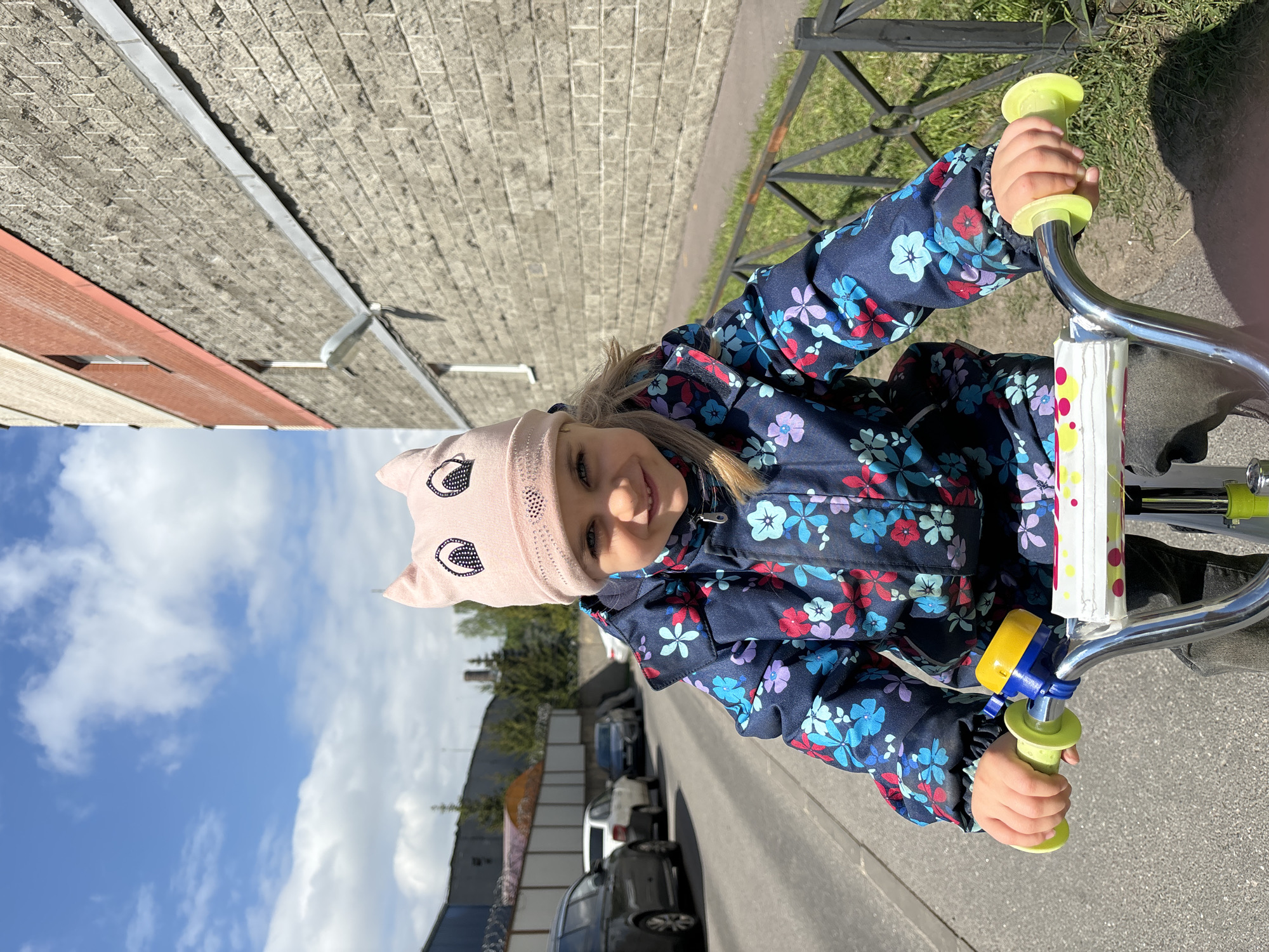 Girl with cat-eared hat bikes around Saint Petersburg with doll