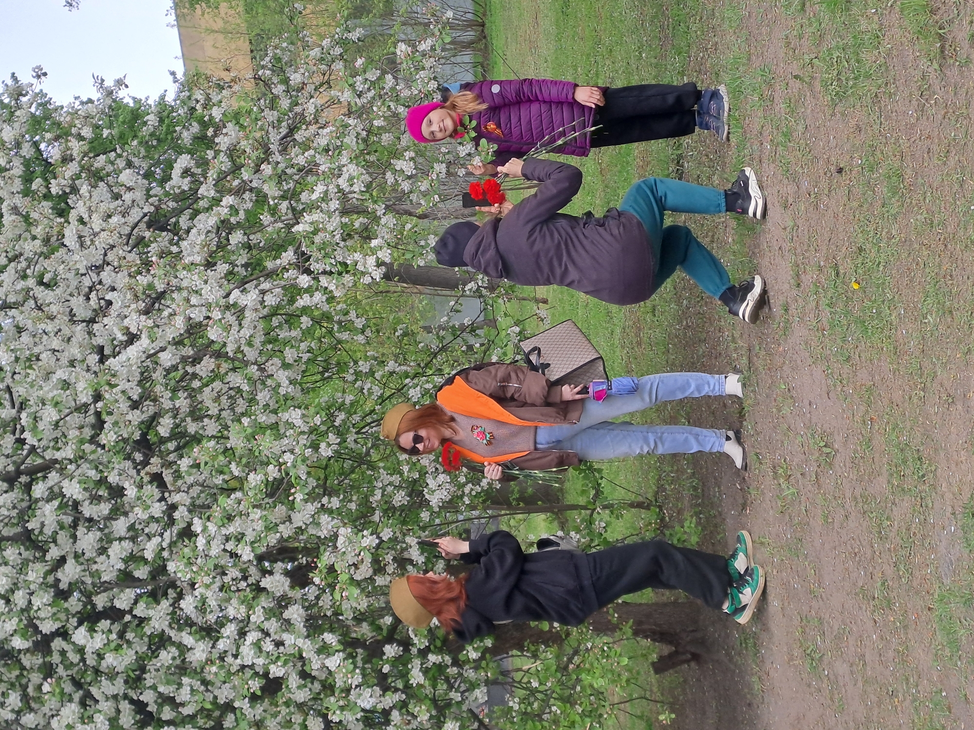 Four people gather near blooming tree in Elektrostal park
