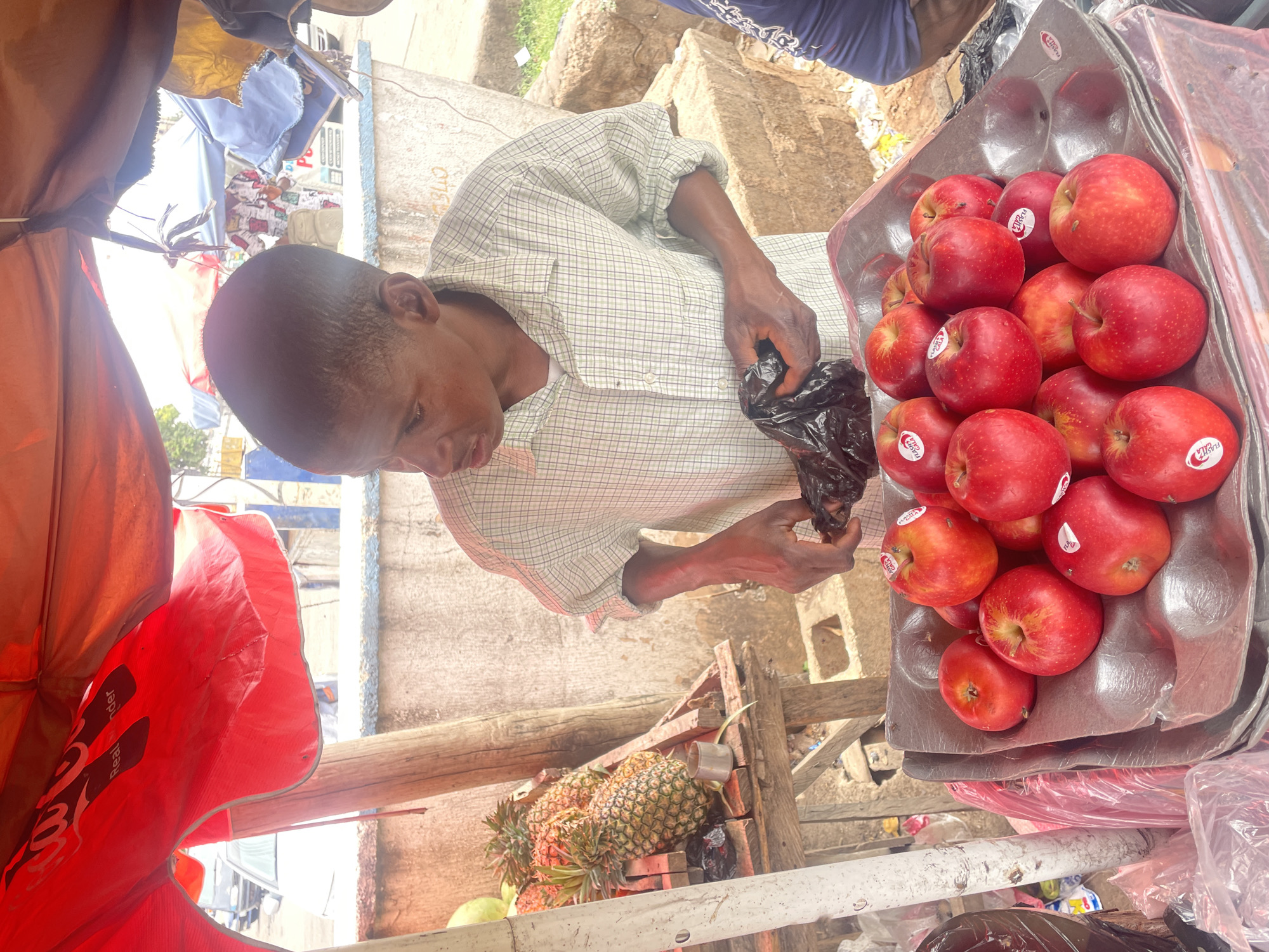 Man inspects bag at apple vendor stall in Jos