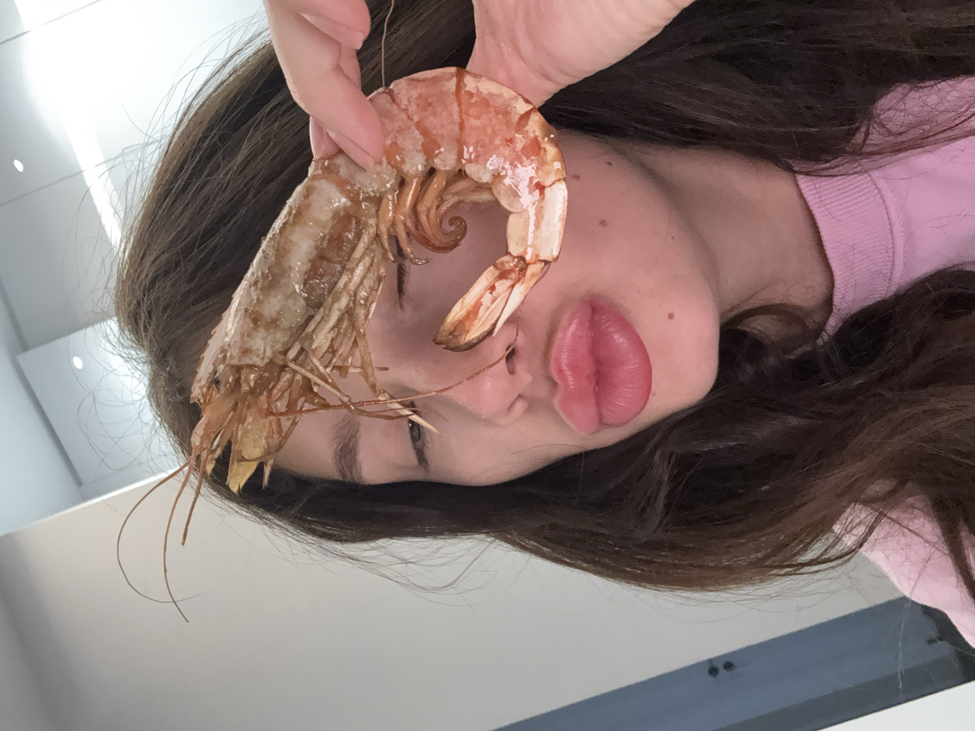 Woman poses playfully with large shrimp in Cyprus