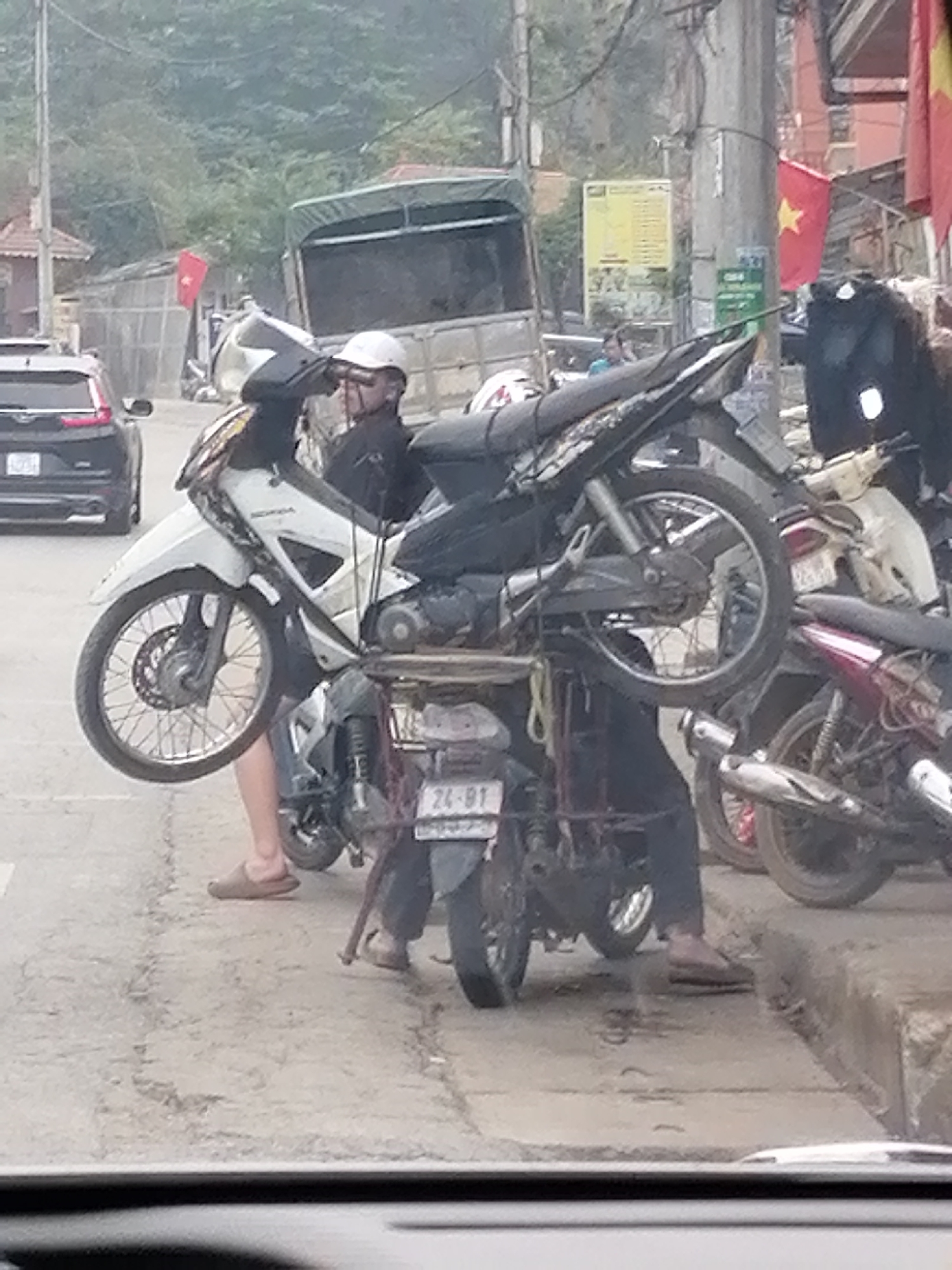 Motorcycle transported on wooden platform atop second bike in Vietnam