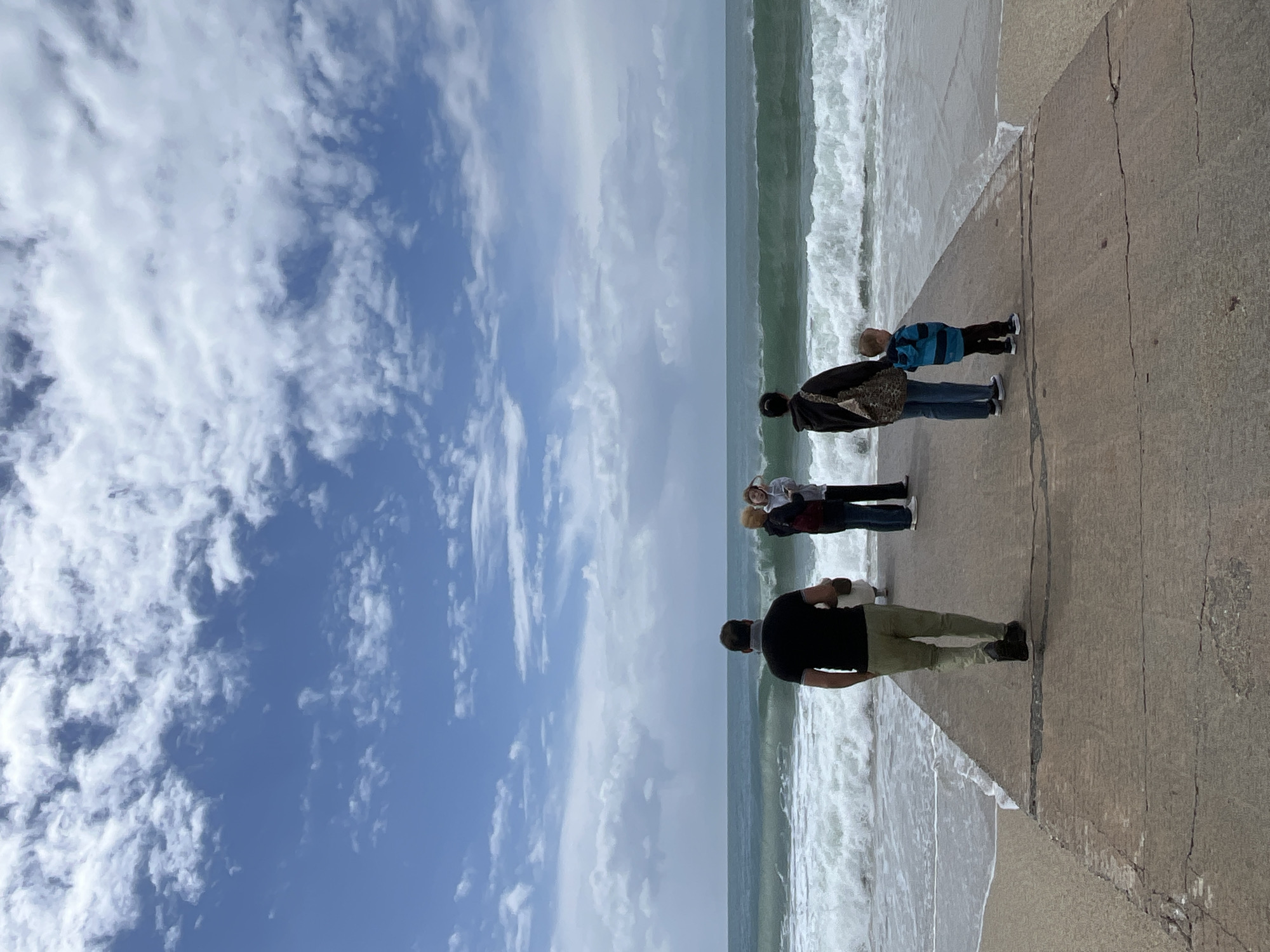 Four people gather on pier overlooking choppy Mediterranean seas