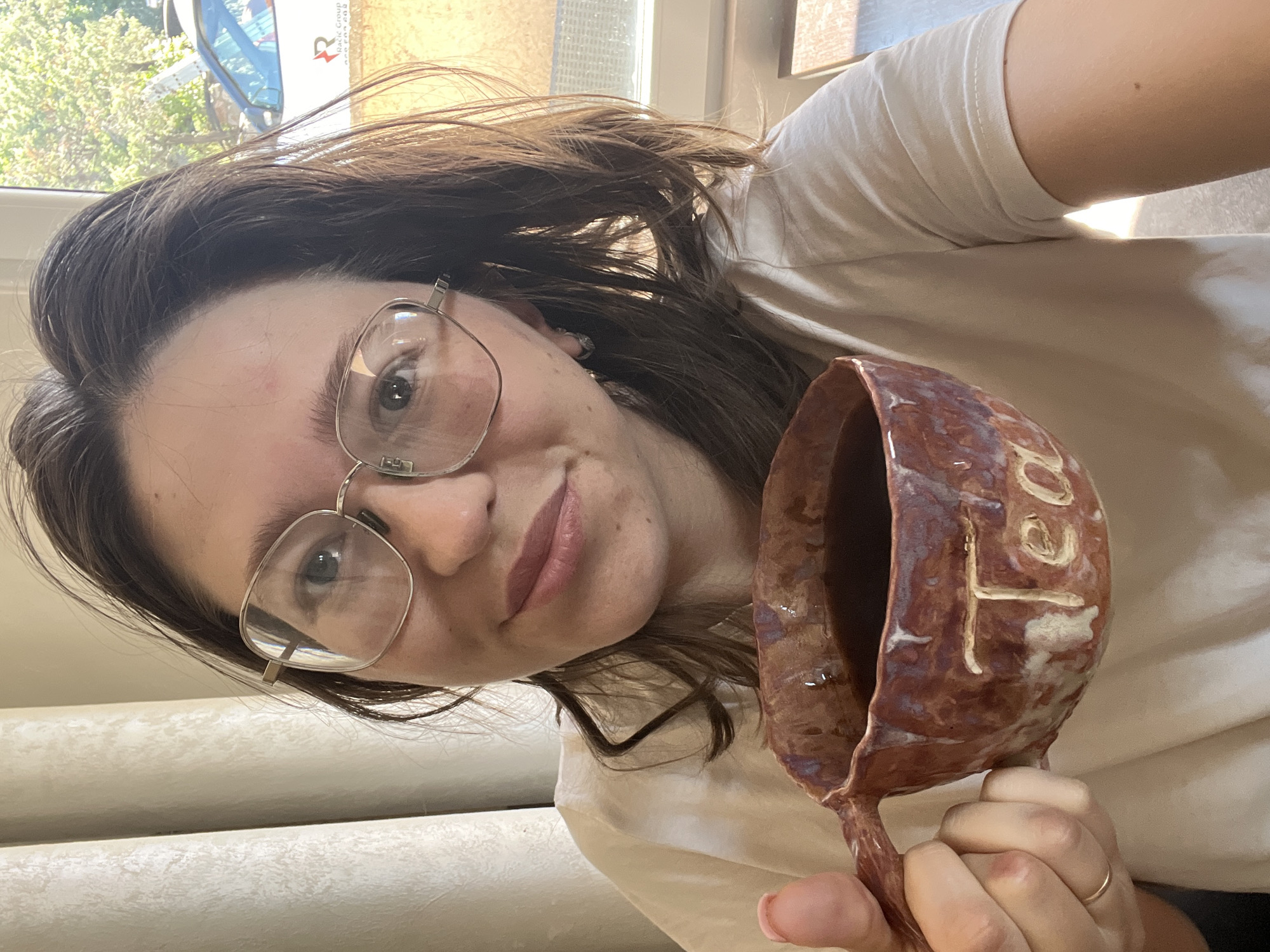 Woman displays ceramic mug indoors in Podgorica