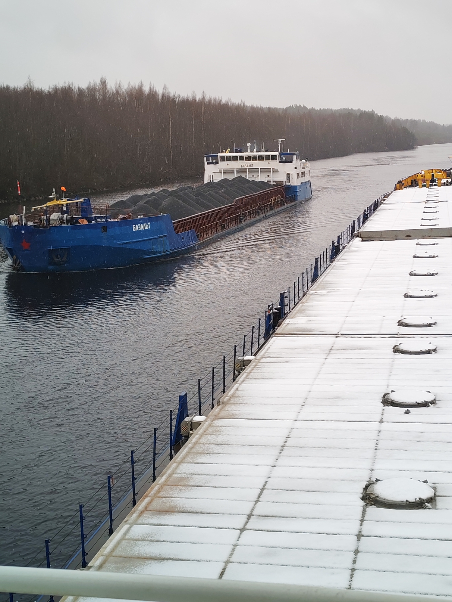 Cargo barge navigates snowy Russian waterway near Volokov Most