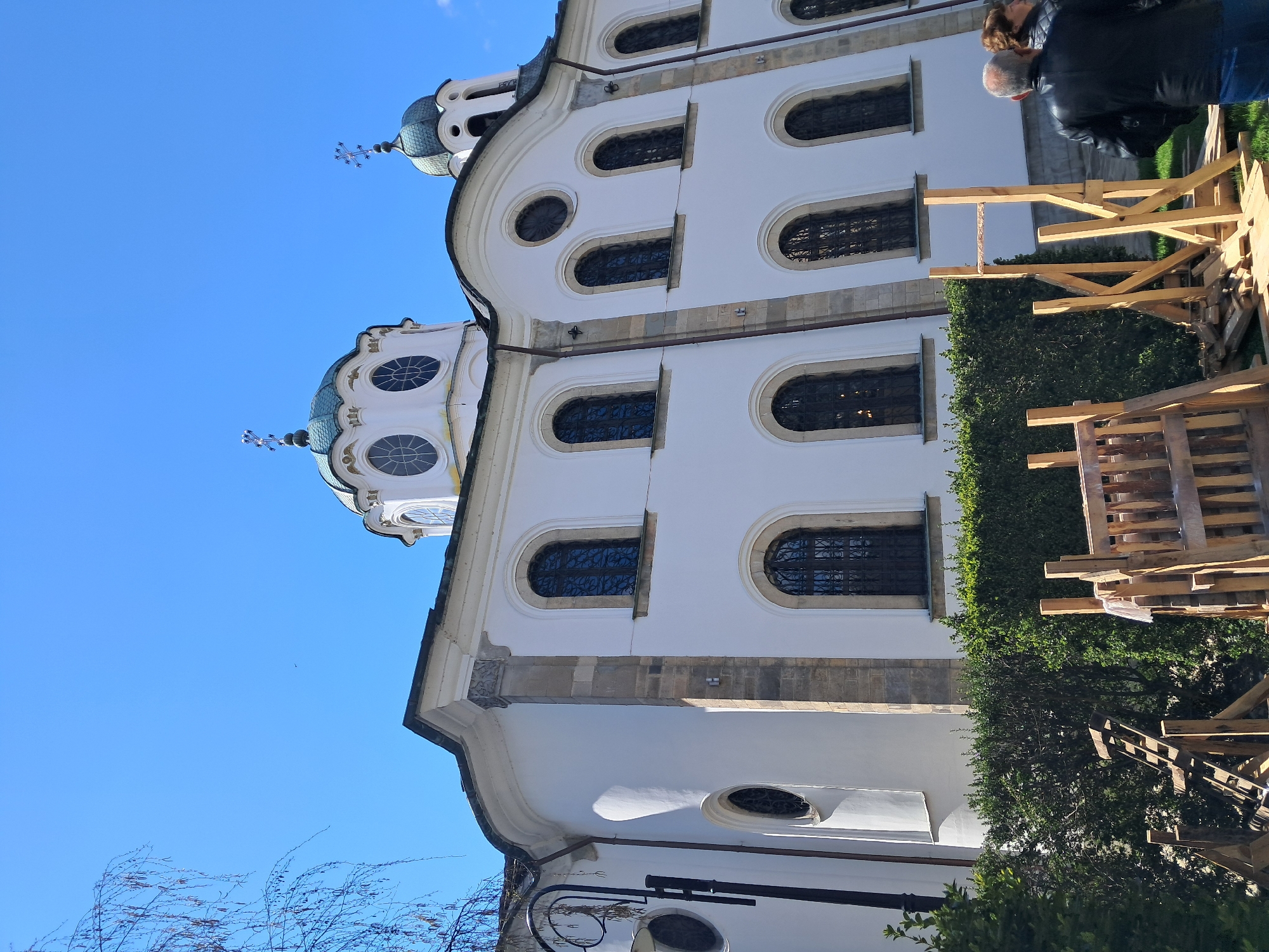 White domed building observed amid construction materials and foliage