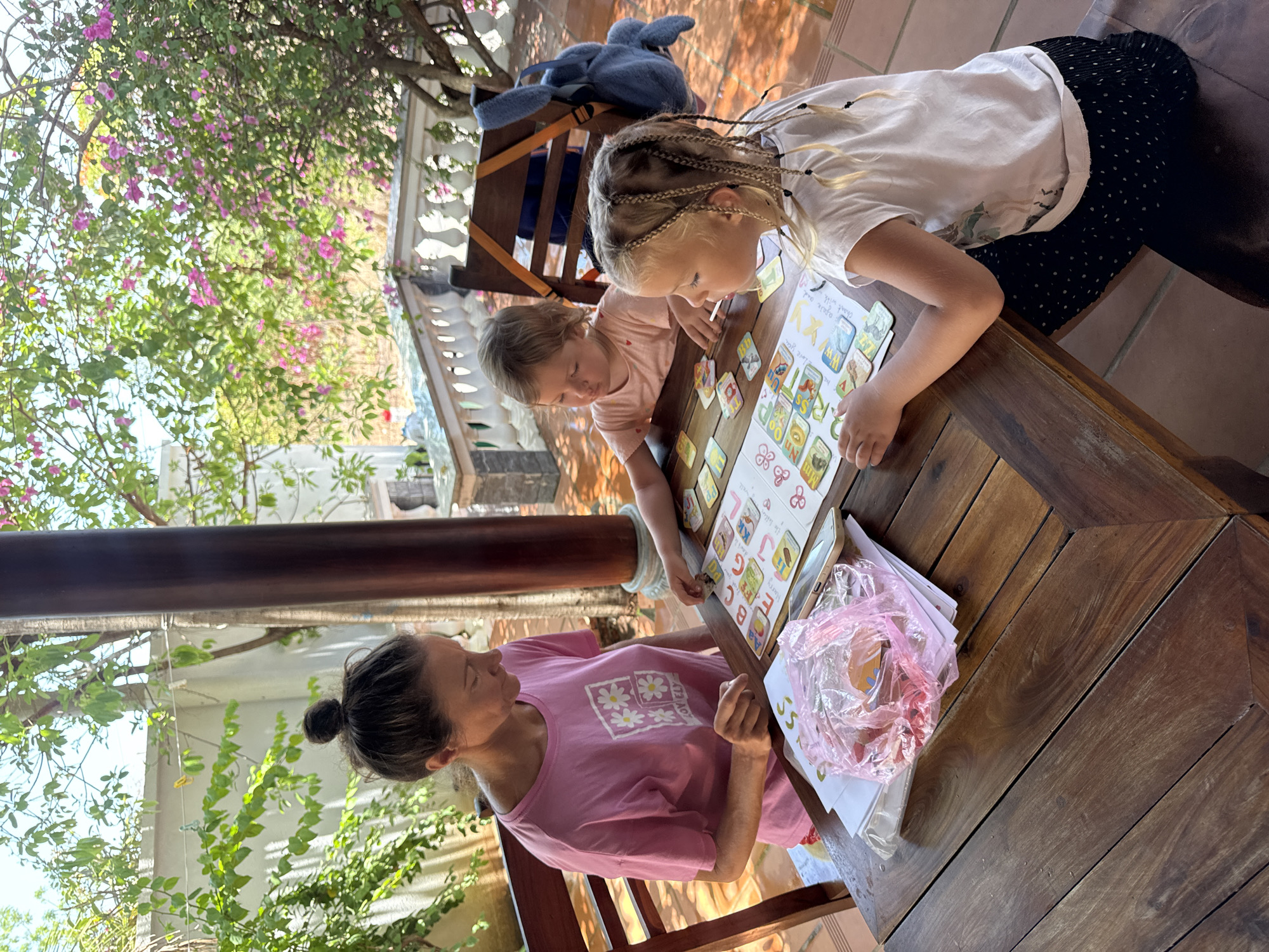 Woman, children play card games on patio in Vietnam