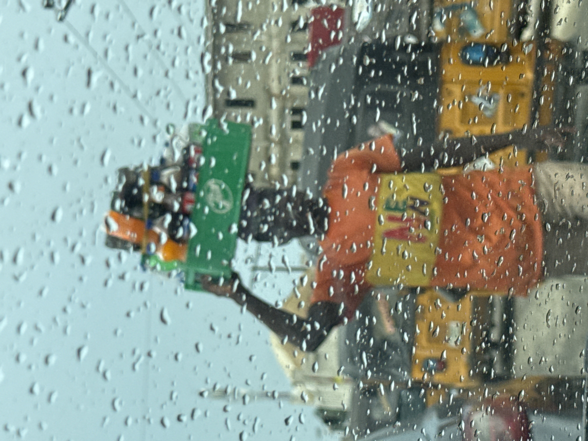 Street vendor carries bottles in basket during rain in Ado