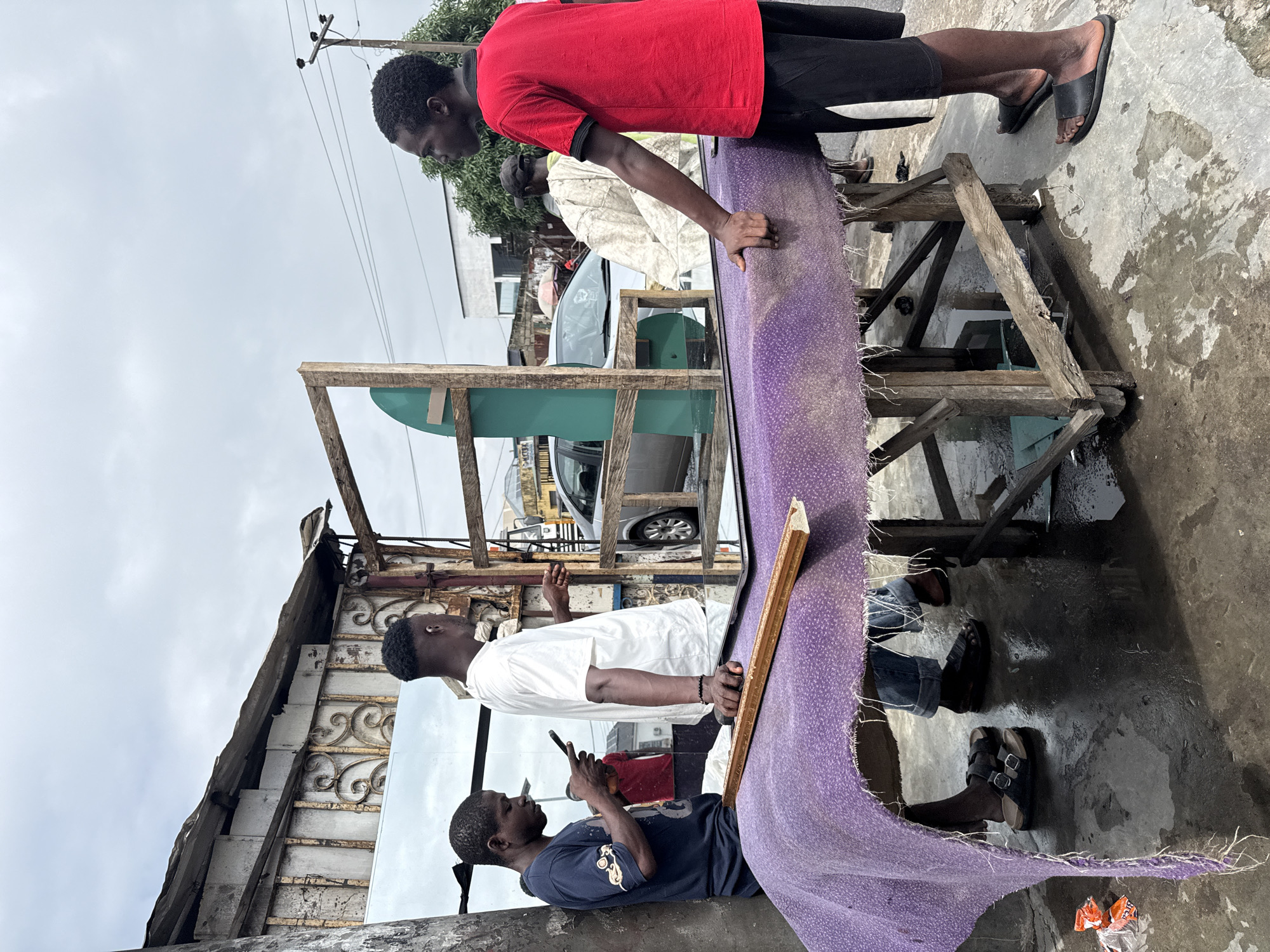 Wet morning street activity across a busy Ado, Nigeria neighborhood