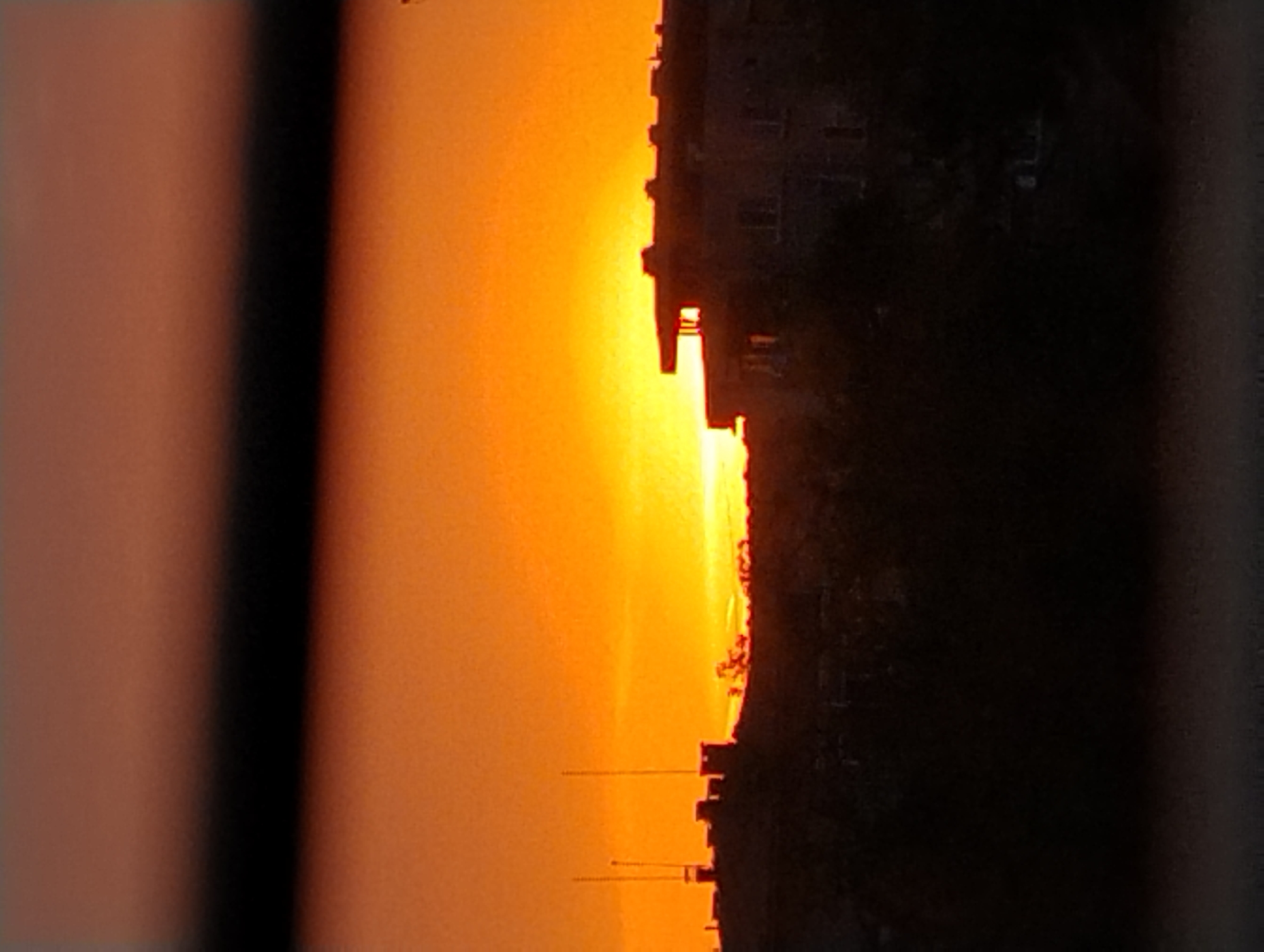 Urban sunset creates orange-yellow sky backdrop for silhouetted towers