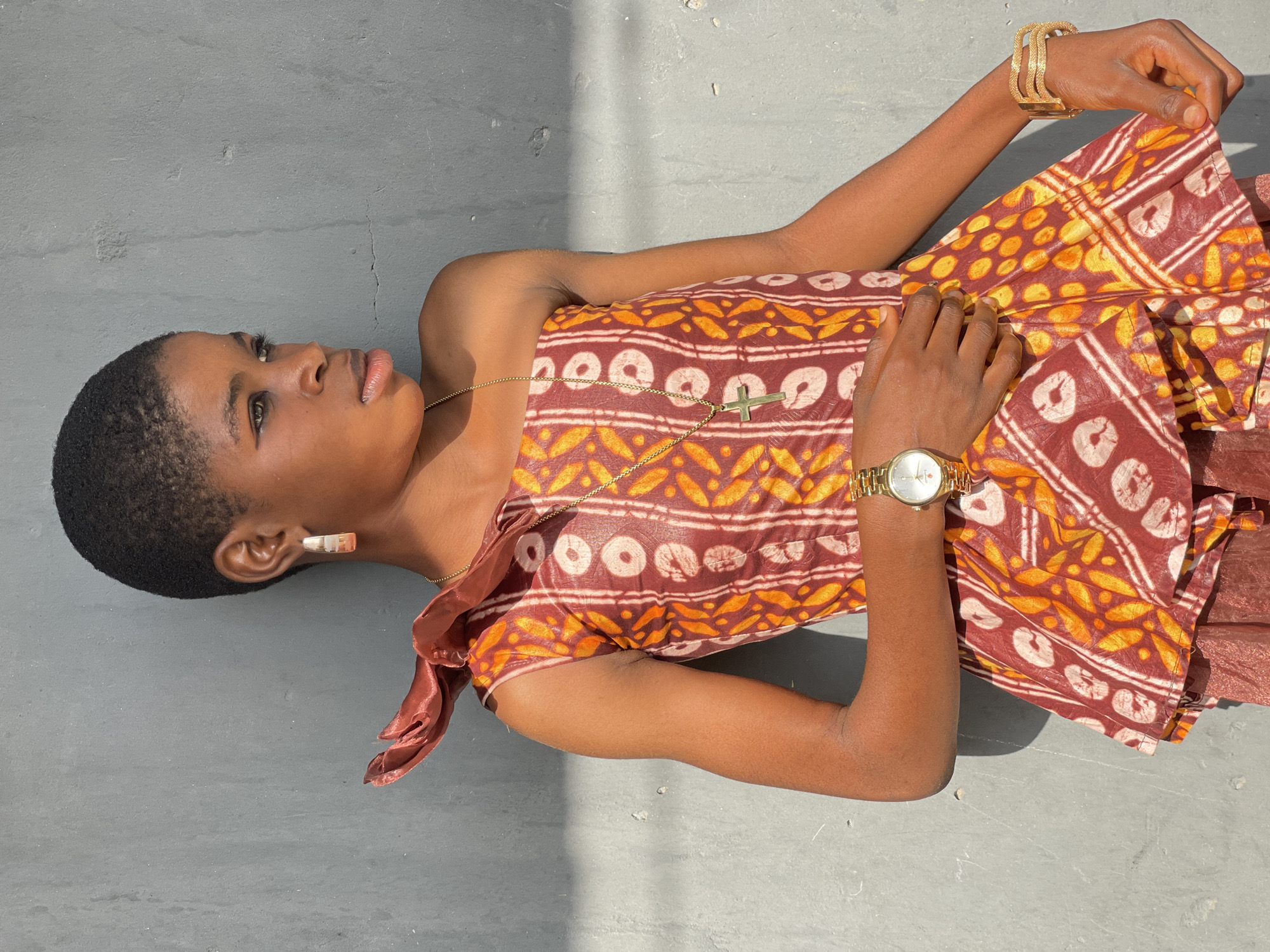 Woman lies on concrete surface in bright sunlight, Badagry