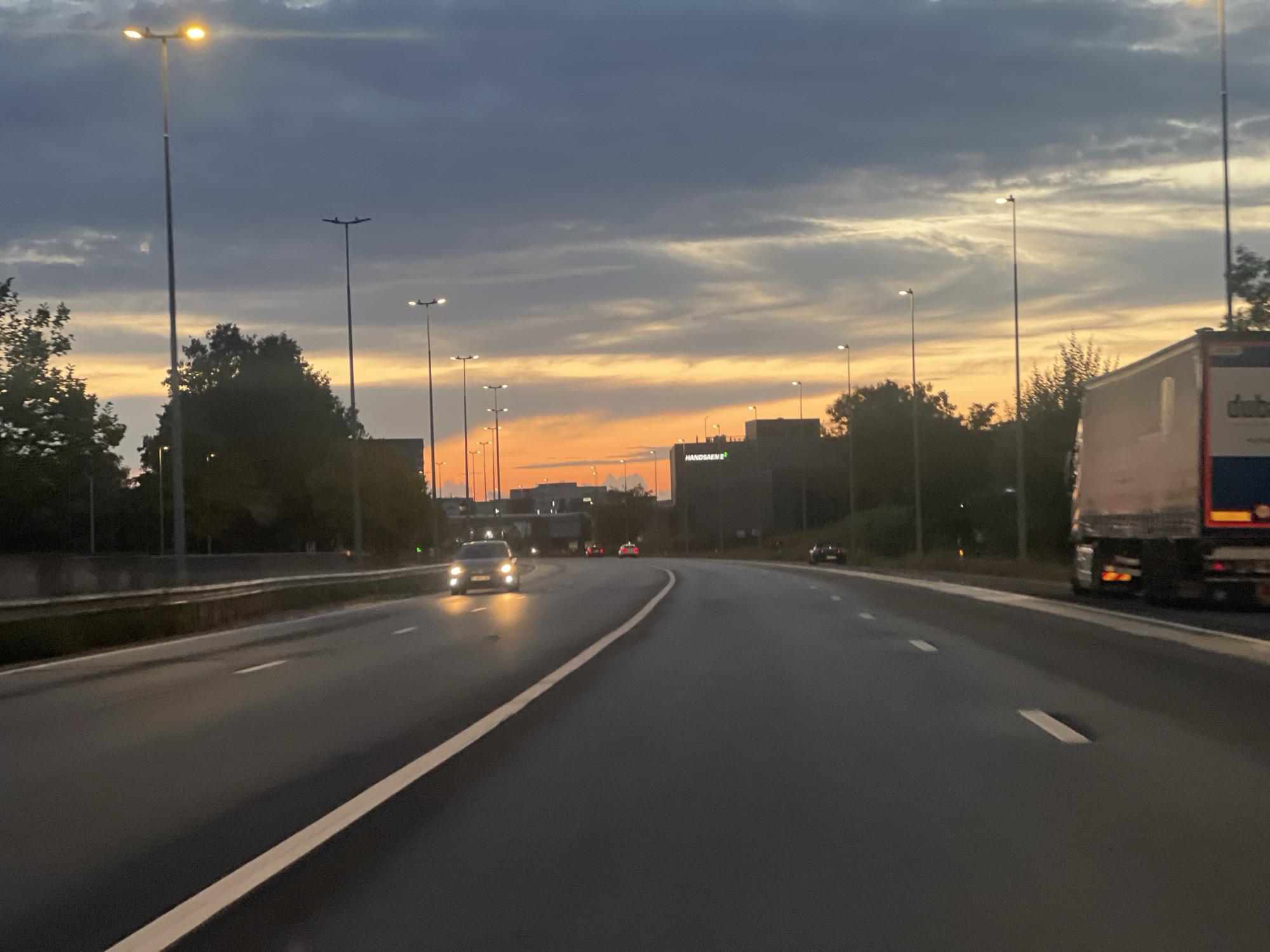 Wet highway drive through a dramatic dusk sky