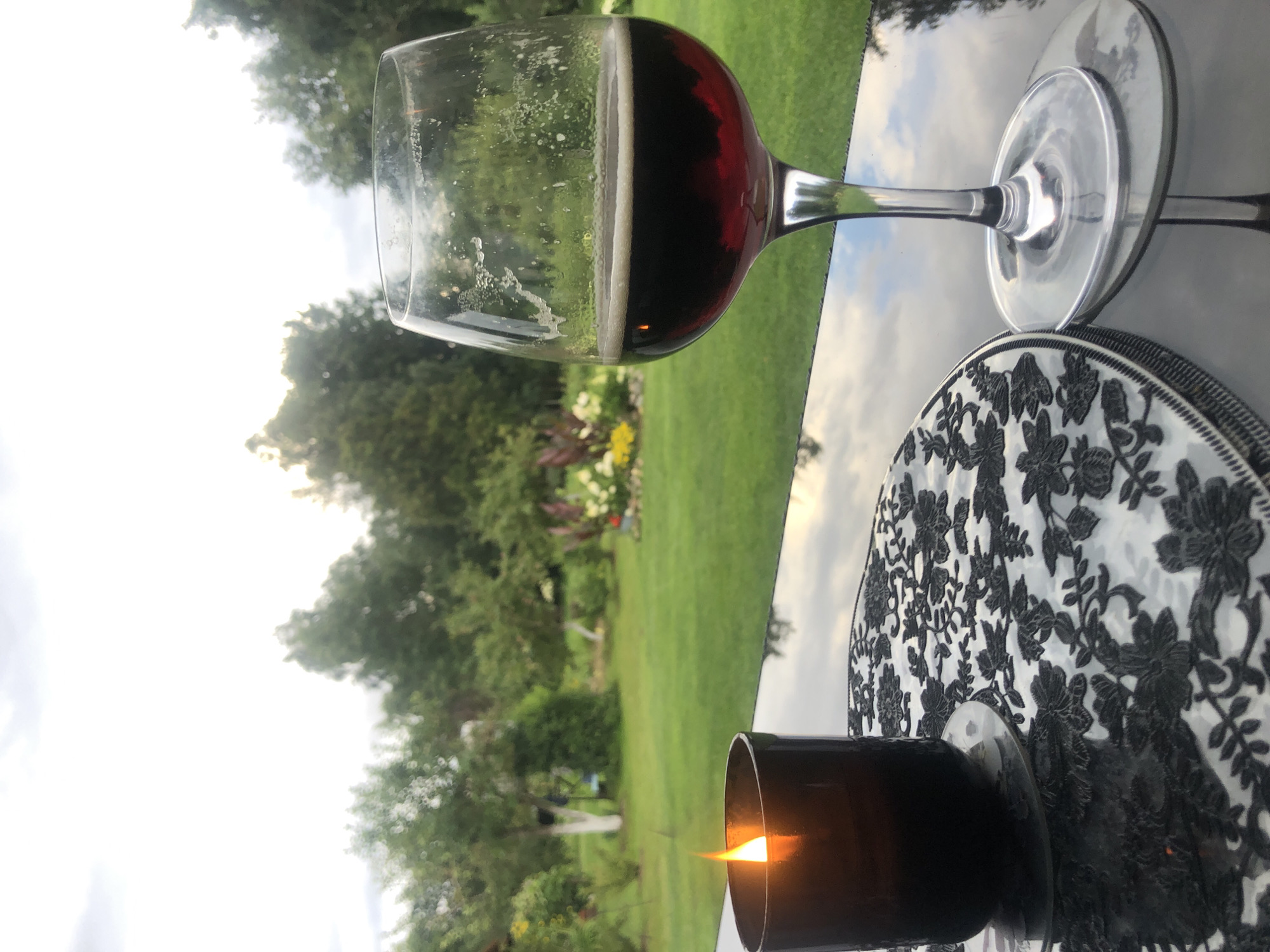 Candle and drink on a reflective surface in an overcast garden