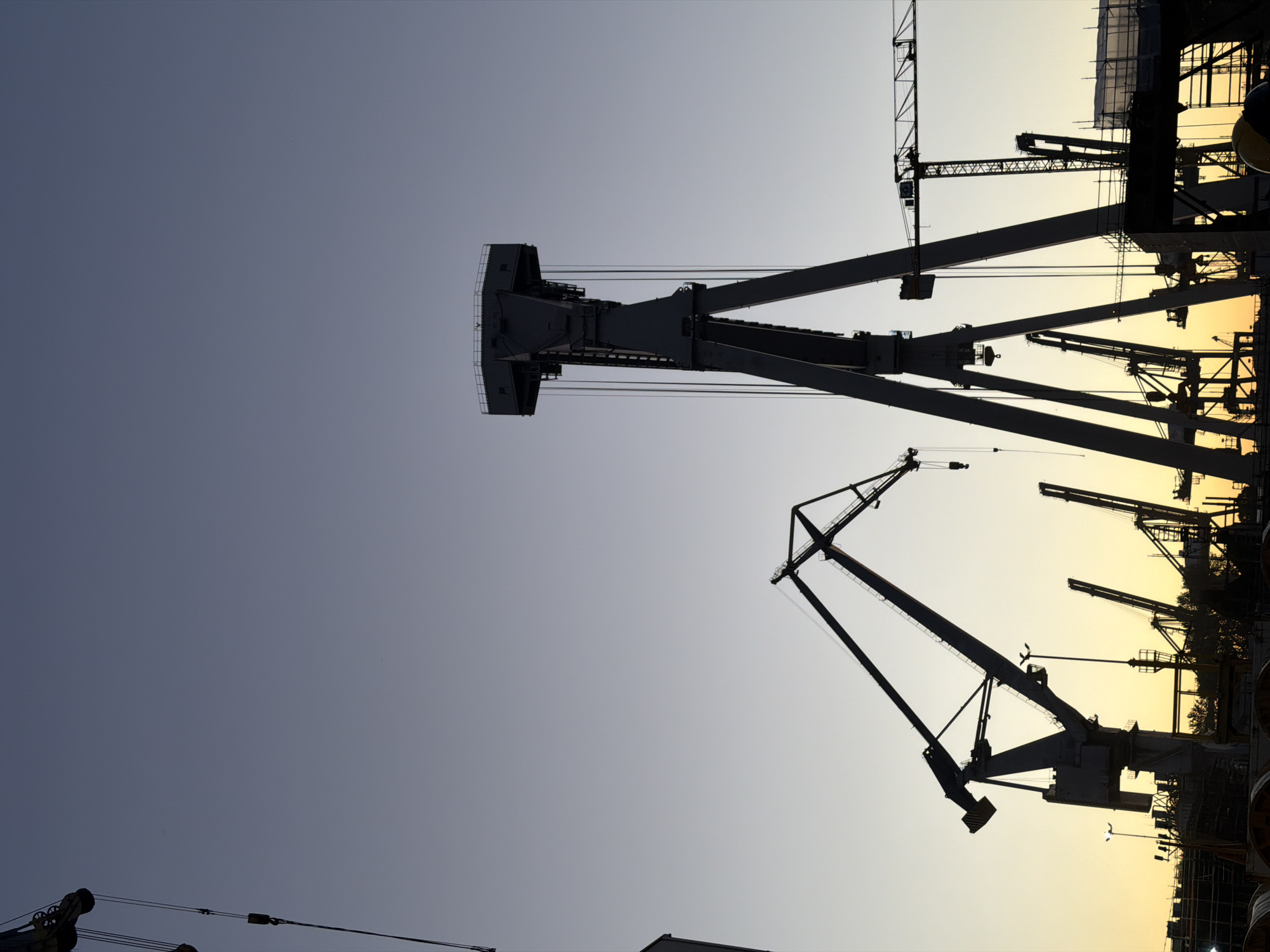 Gdynia shipyard cranes cut silhouettes against a twilight sky