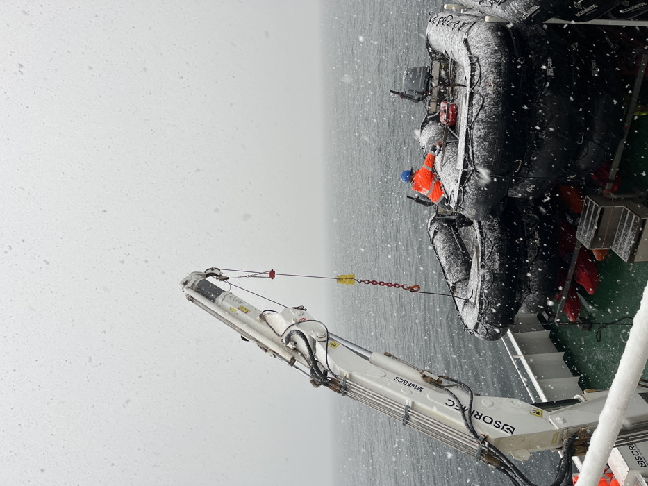 Crane lifts snow-covered boats in maritime operation